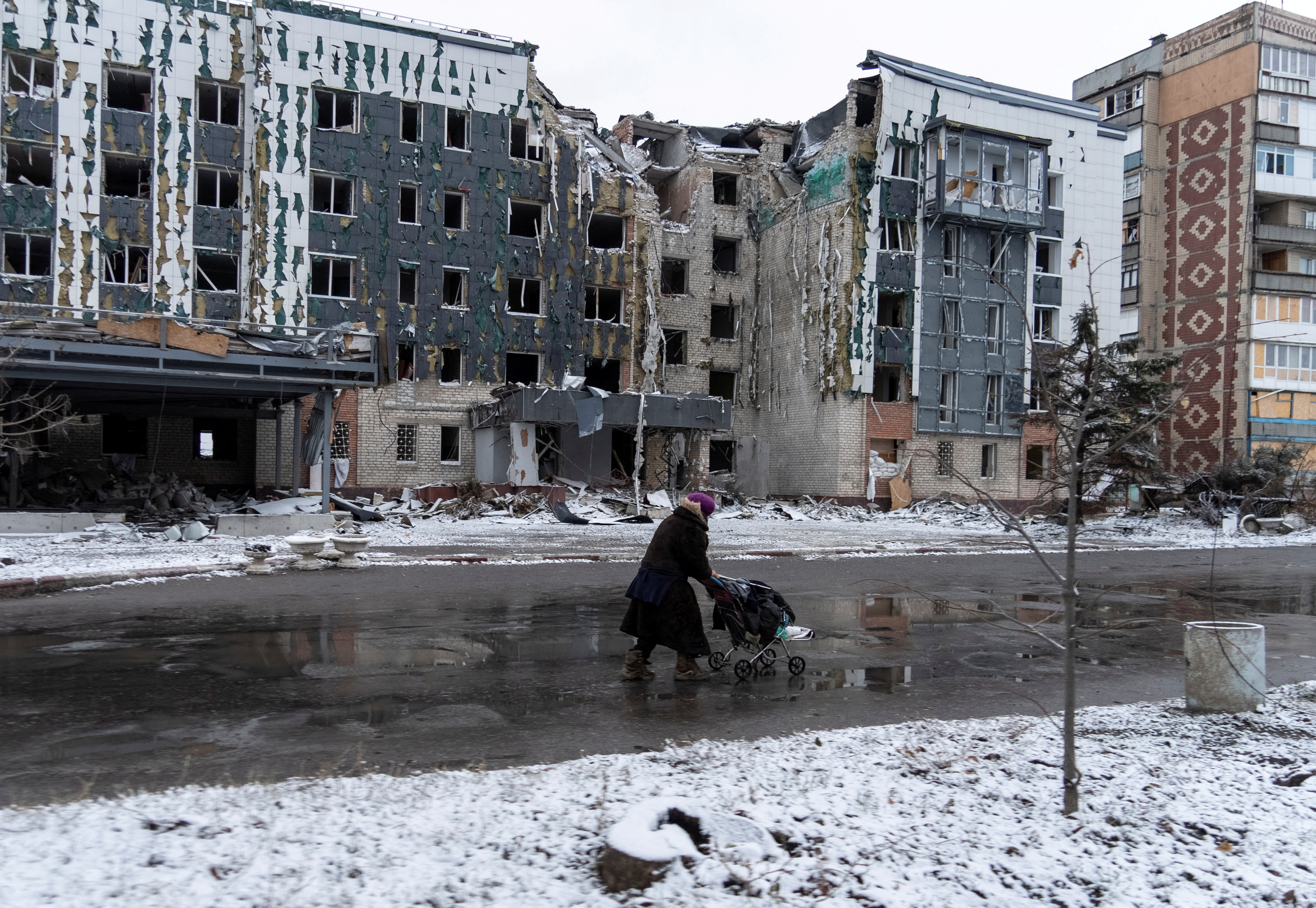 FILE PHOTO: A woman walks past a building damaged by a Russian military strike in the town of Pokrovsk