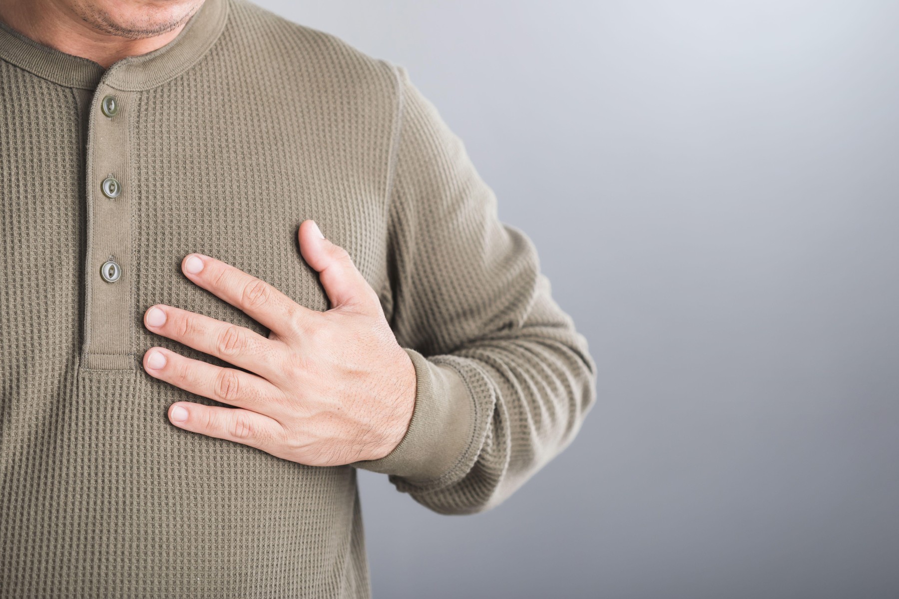A man touches his left chest, indicating pain that may signal heart or cardiovascular issues. Image emphasizes the importance of early detection and a