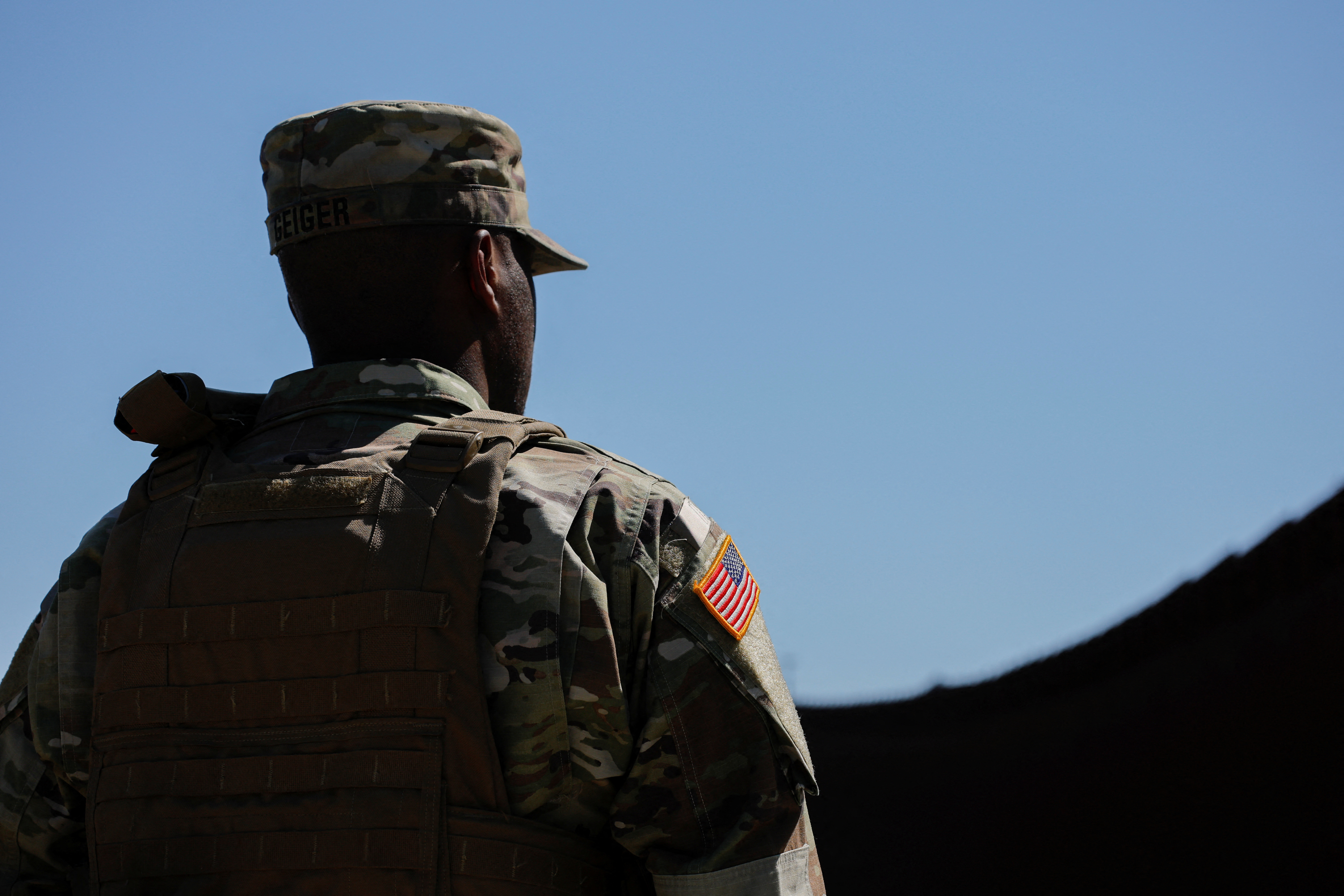 A member of the U.S. Army stands facing the border wall between Mexico and the United States, whcih has been reinforced by the U.S. Military, in San Dieg