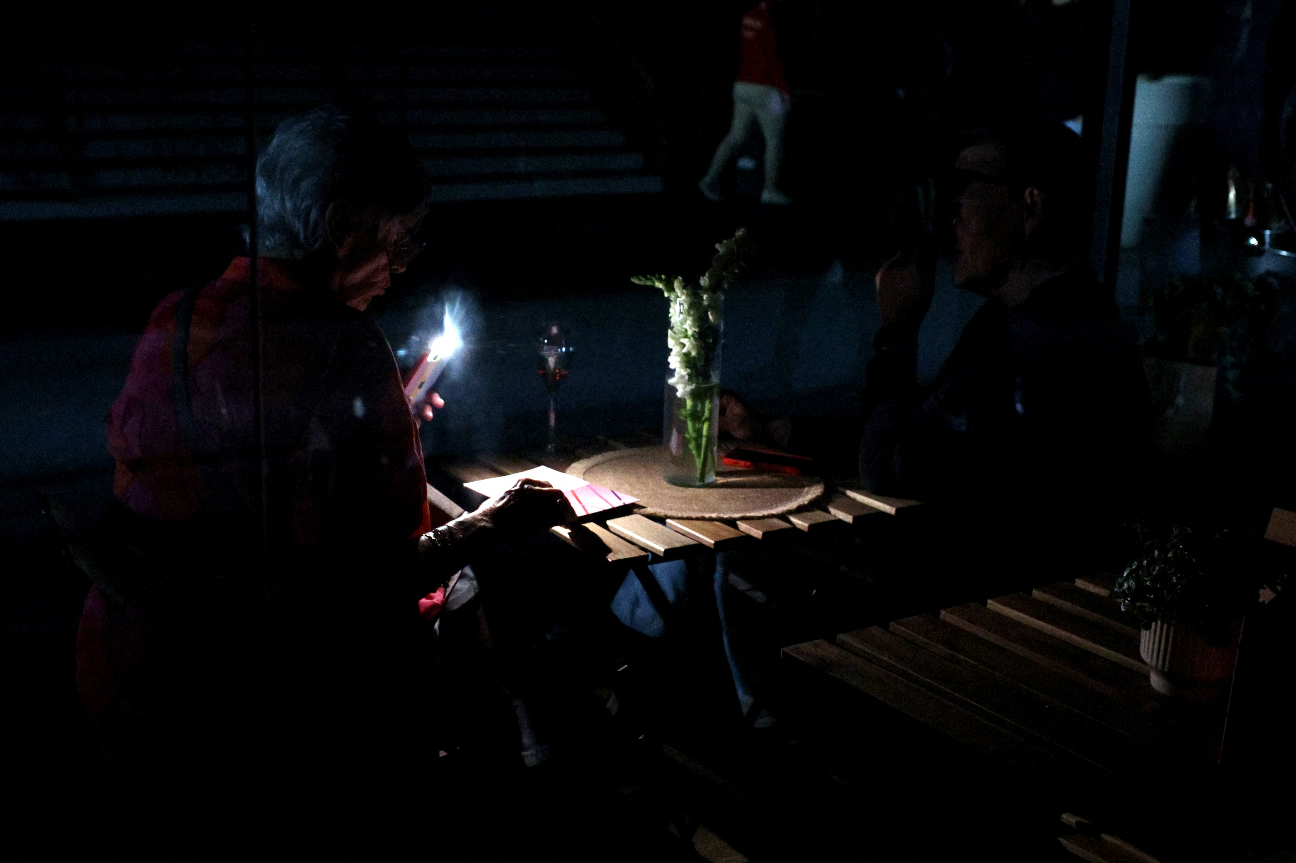 Žena u mraku bljeskalicom osvjetljava knjigu