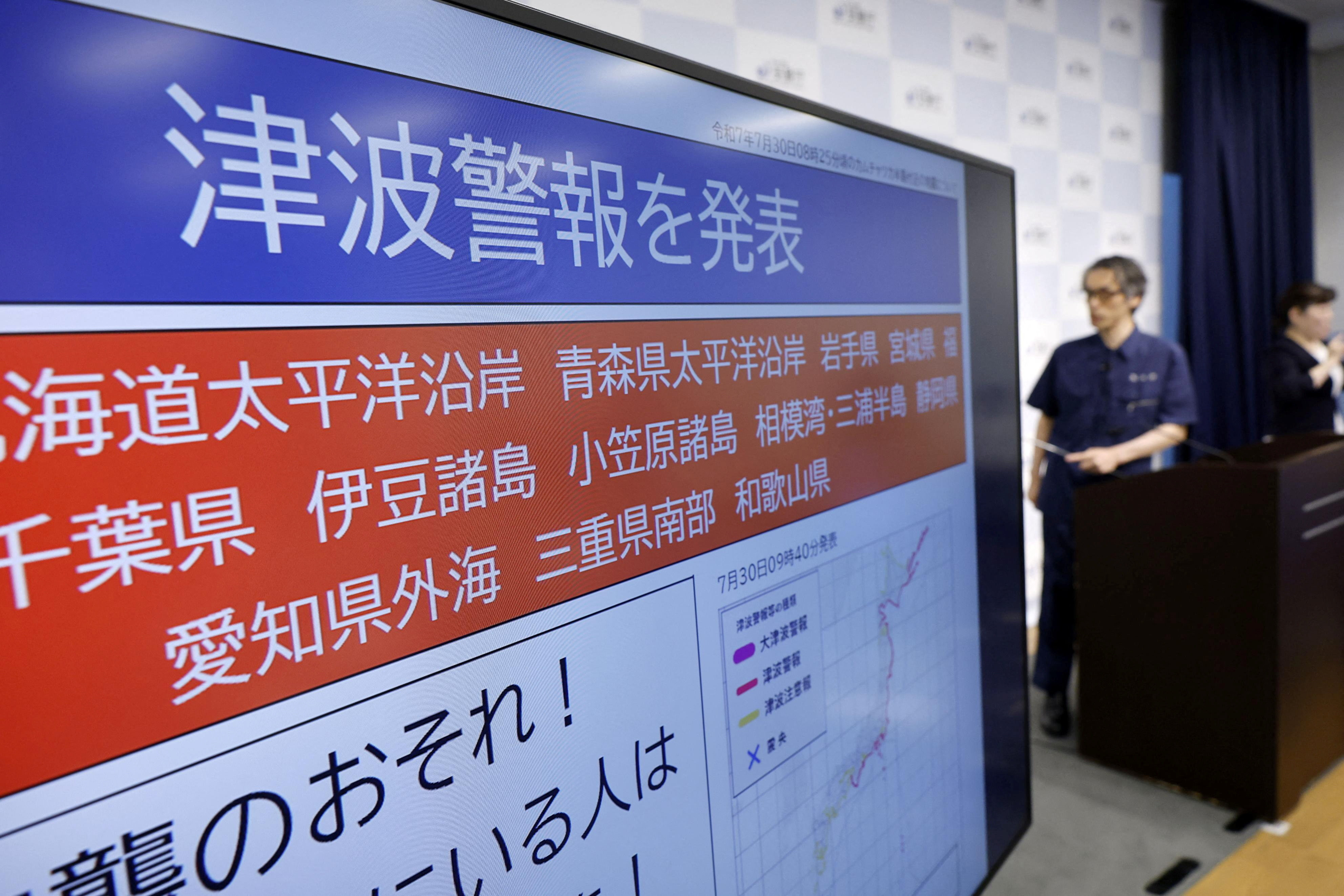 A screen reading "Tsunami alert announced" is displayed as a Japan's meteorological agency staff member attends a press conference, after Japan issued evacuation alert following major quake in Russia's Kamchatka Peninsula