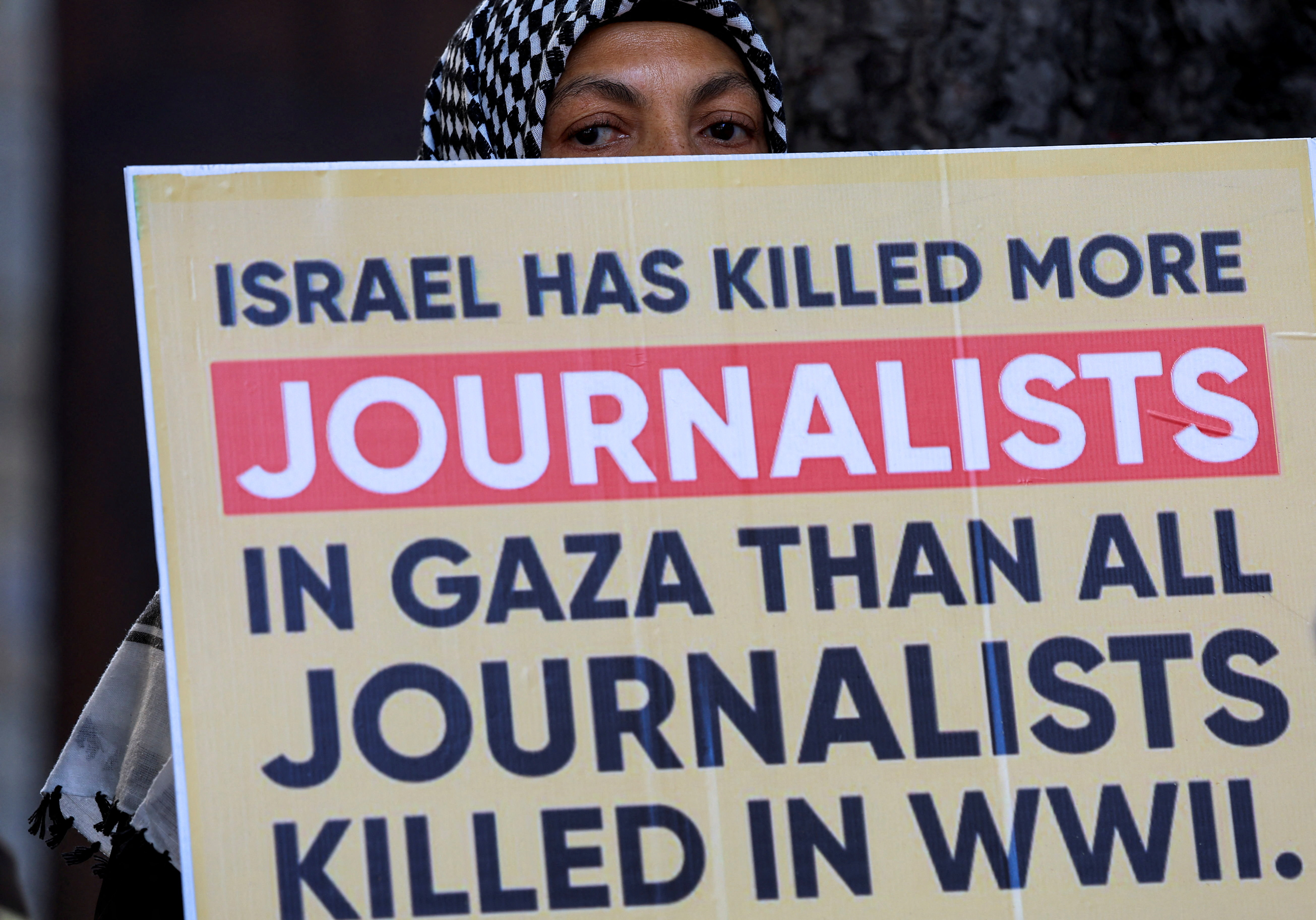 A person holds a placard during a vigil in solidarity with journalists killed in Gaza, outside St George’s Cathedral in Cape Town, South Africa, August 13, 2025