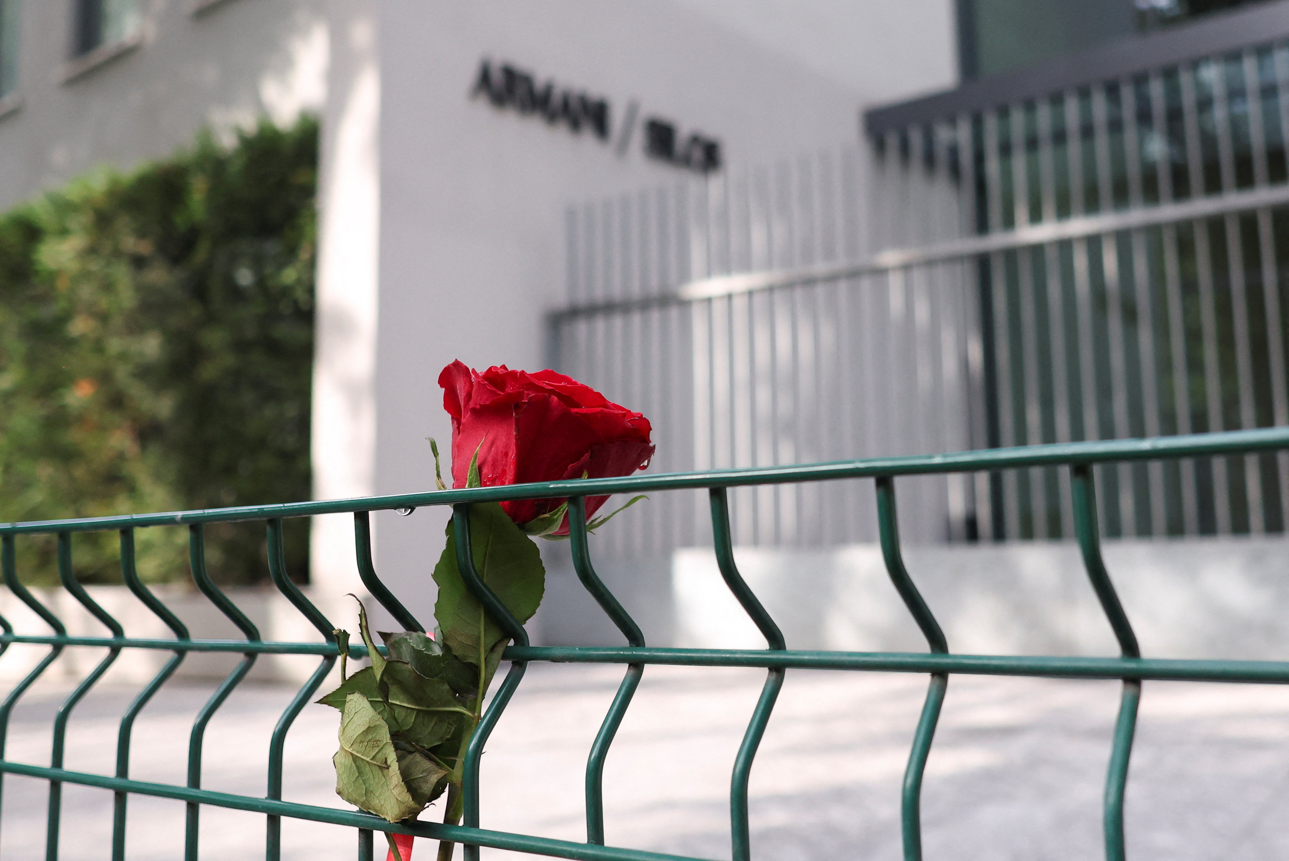 A rose is attached to a fence in front of the Armani/Silos following the death of Giorgio Armani at the age of 91, in Milan, Italy, September 5, 2025. REUTERS/Claudia Greco