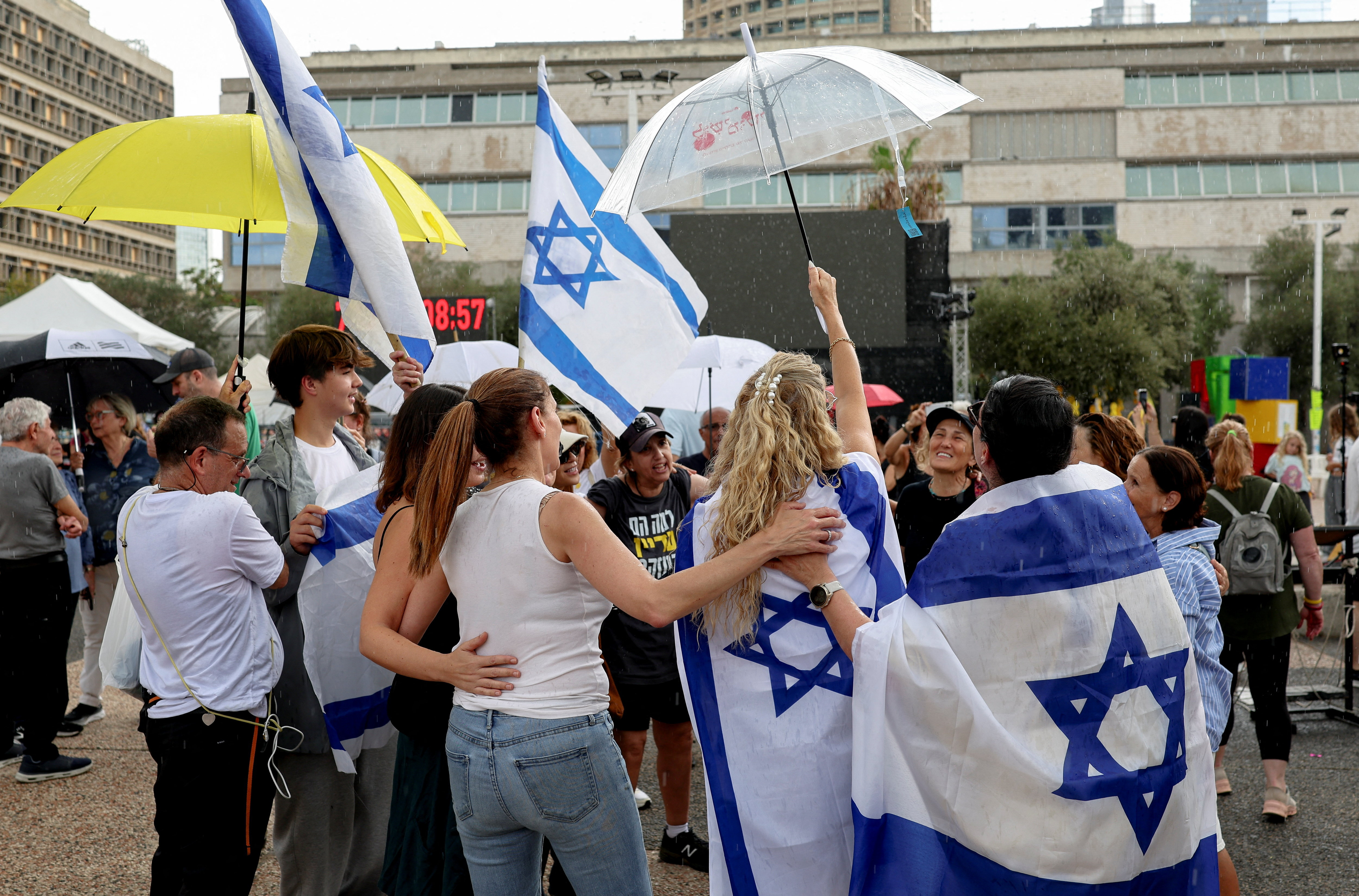 People celebrate holding Israeli flags after U.S. President Donald Trump announced that Israel and Hamas agreed on the first phase of a Gaza ceasefire, at the "Hostages square", in Tel Aviv, Israel, October 9, 2025. REUTERS/Ronen Zvulun