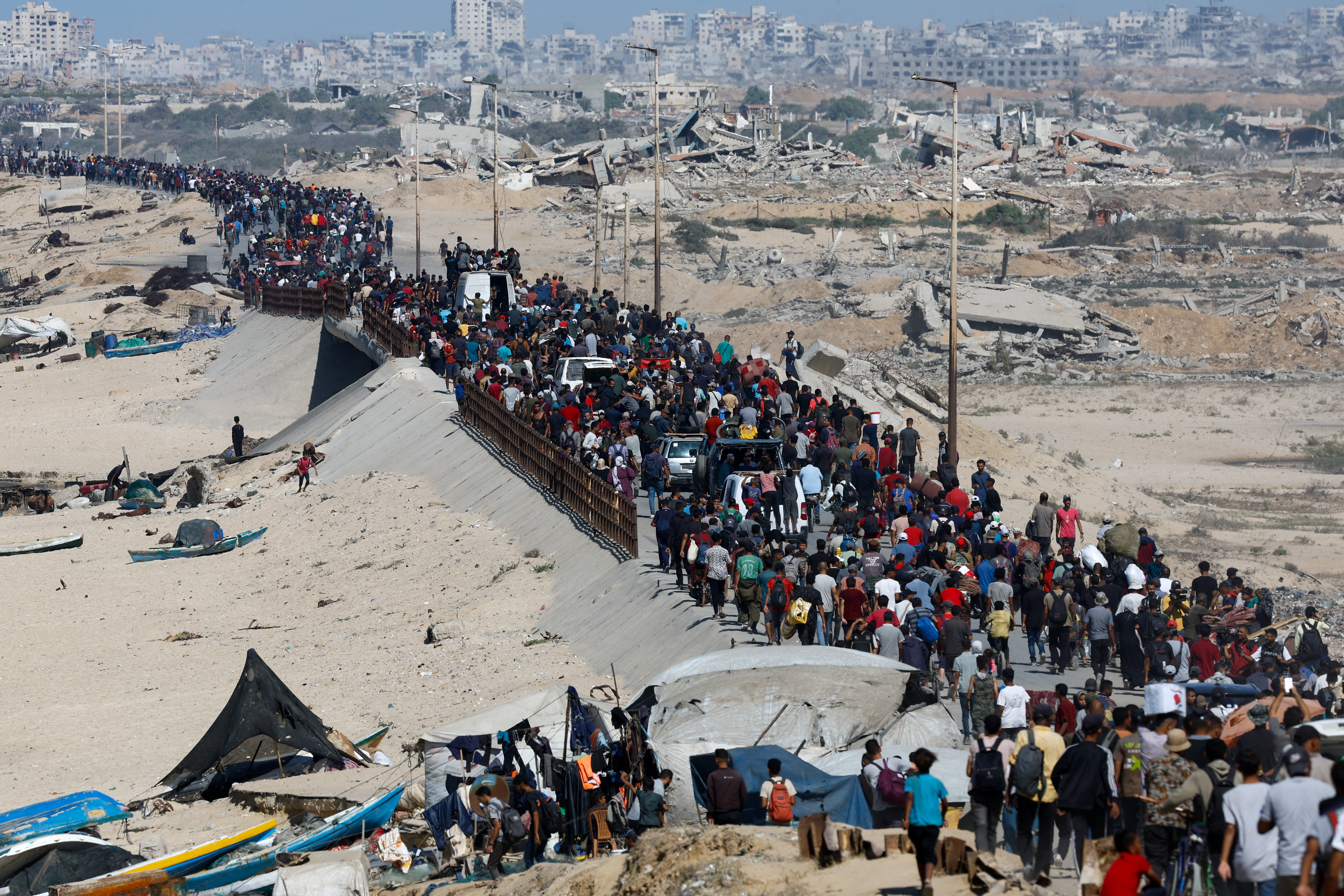 Palestinians, who were displaced to the southern part of Gaza at Israel's order during the war, make their way along a road past destroyed buildings as they return to the north after a ceasefire