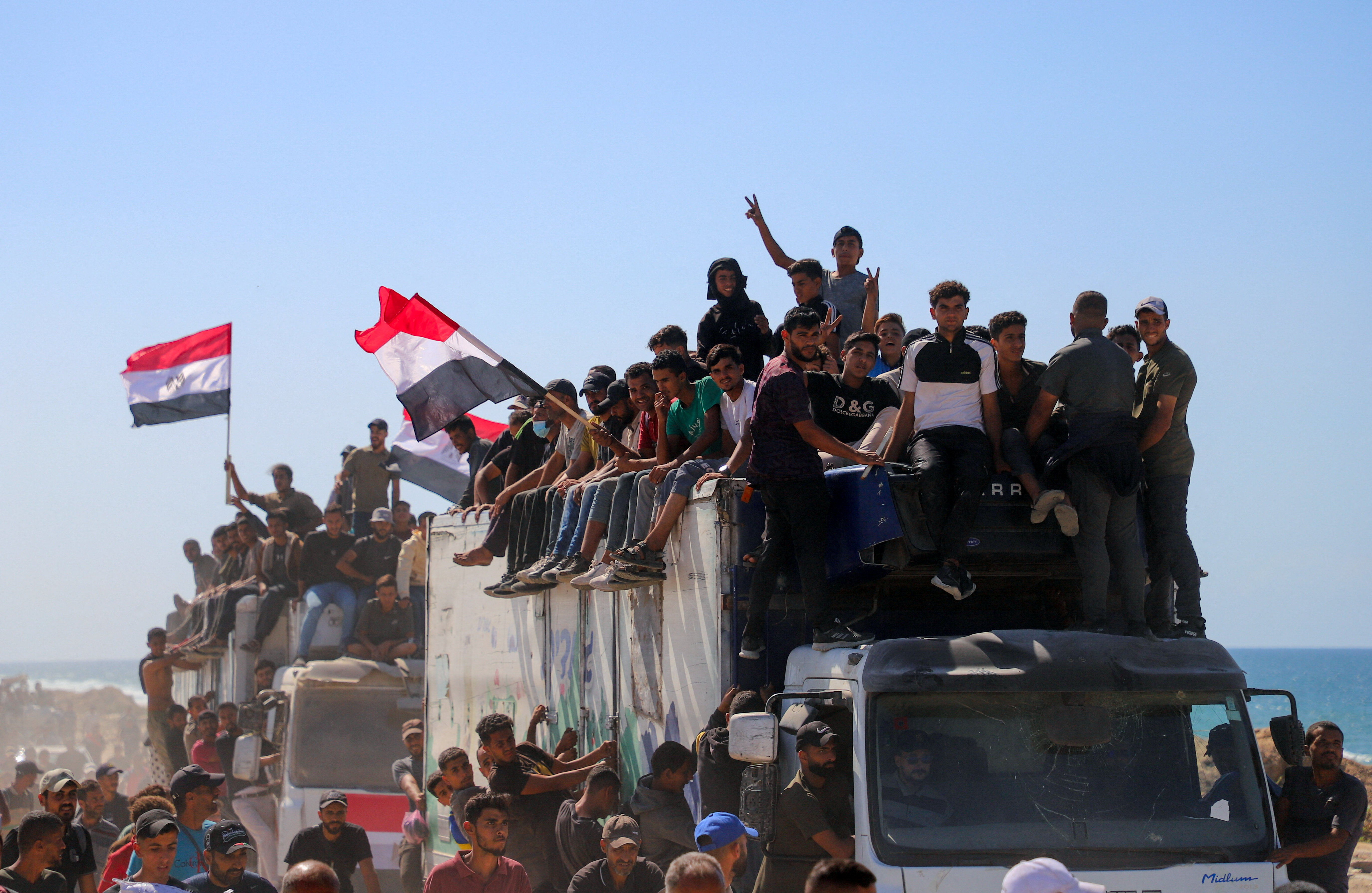 Palestinians, who were displaced to the southern part of Gaza at Israel's order during the war, hold Egyptian flags as they ride on vehicles