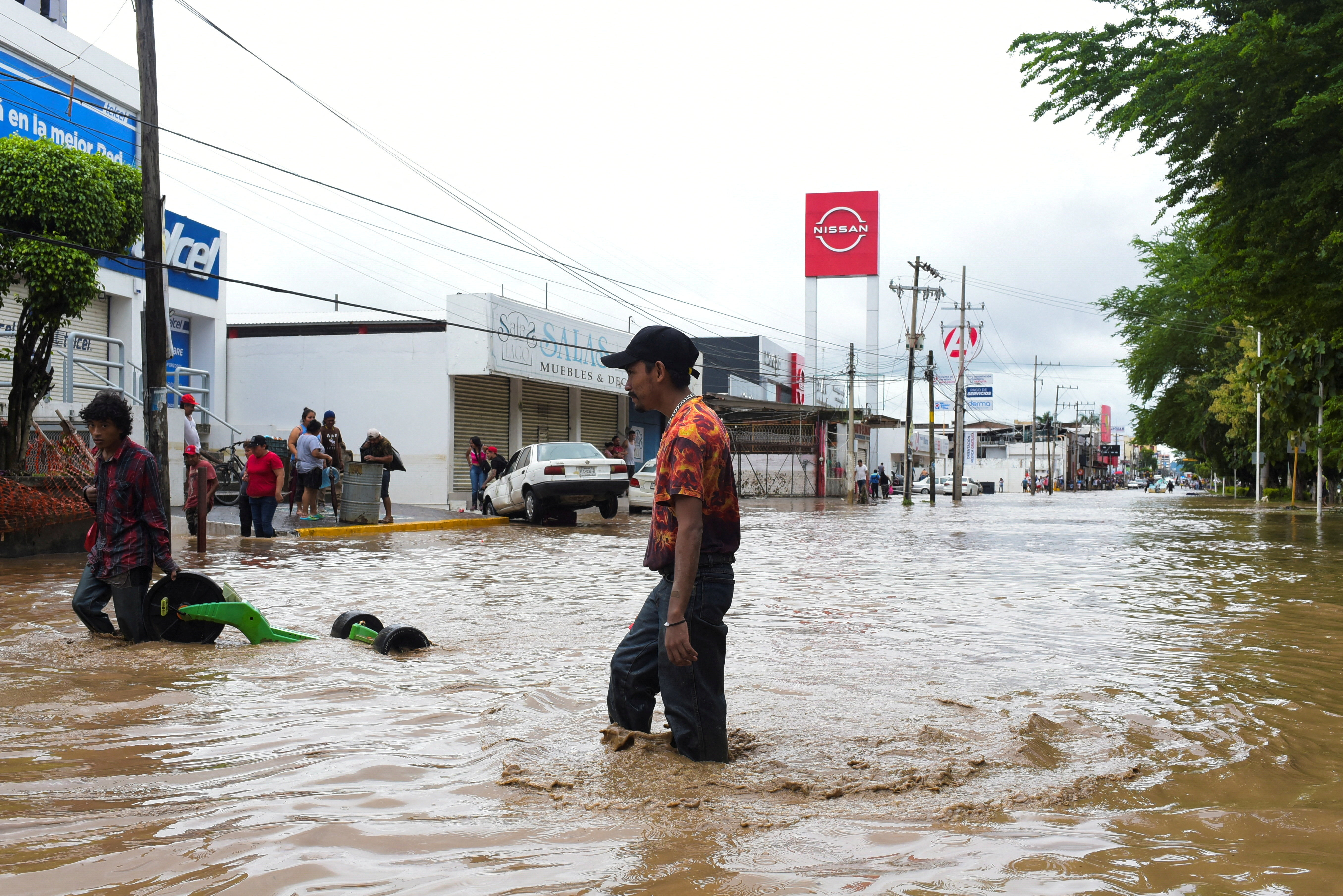 People wade through a flooded street after torrential rains that caused an overflow of rivers in Poza Rica, Veracruz state, Mexico, October 10, 2025. REUTERS/Rolando Ramos