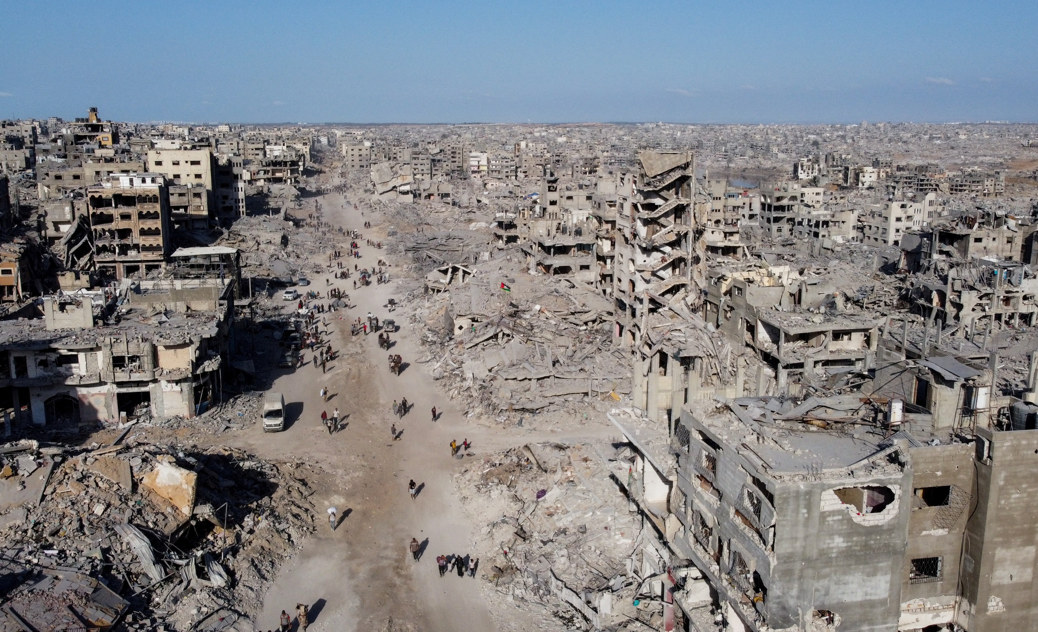 A drone view shows Palestinians walking past the rubble following Israeli forces' withdrawal from the area, amid a ceasefire between Israel and Hamas in Gaza, in Gaza City
