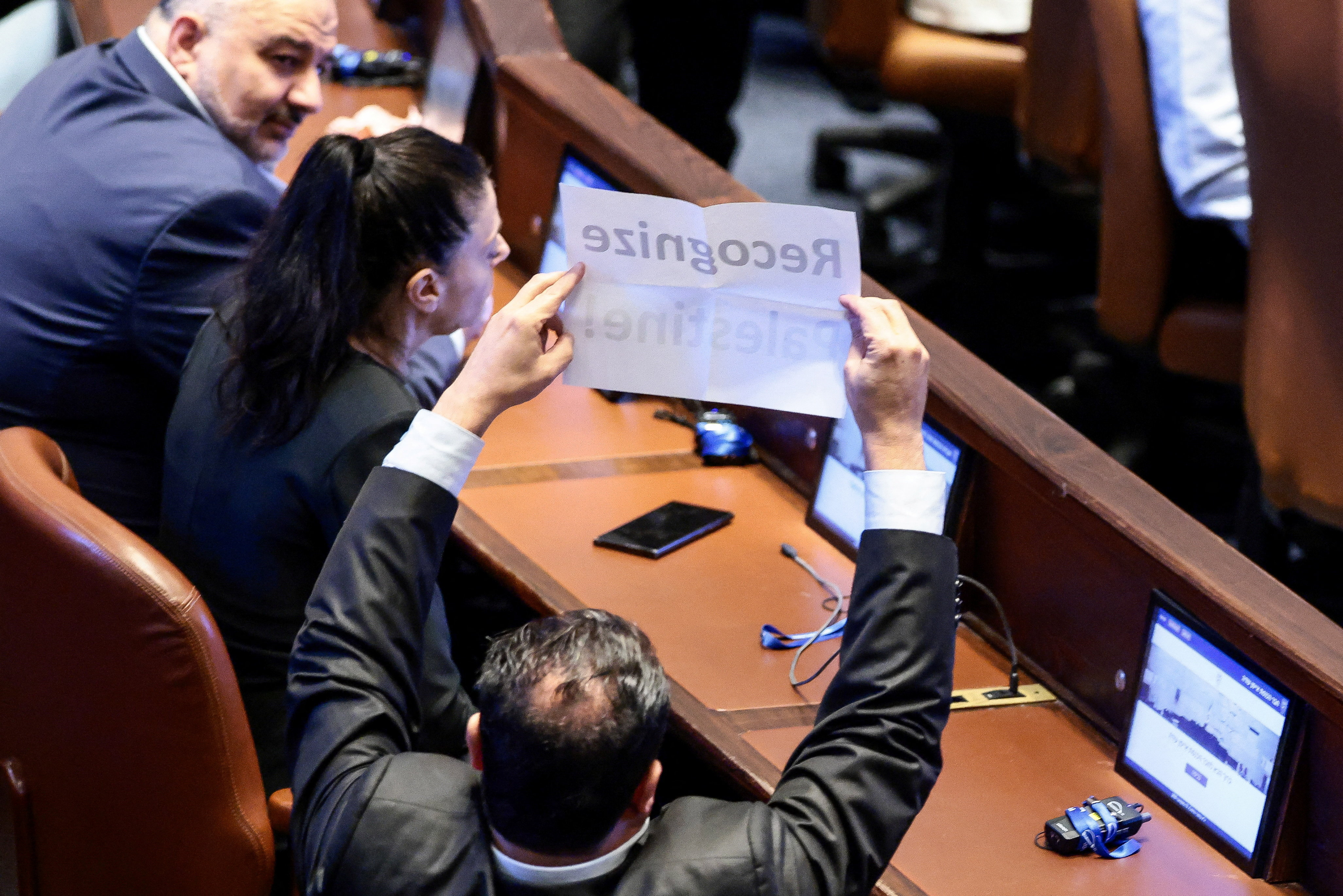 An Israeli member of parliament holds a placard that reads: 'Recognize Palestine!' at the Knesset on the day of U.S. President Donald Trump's address, amid a U.S.-brokered prisoner-hostage swap and ceasefire deal between Israel and Hamas, in Jerusalem