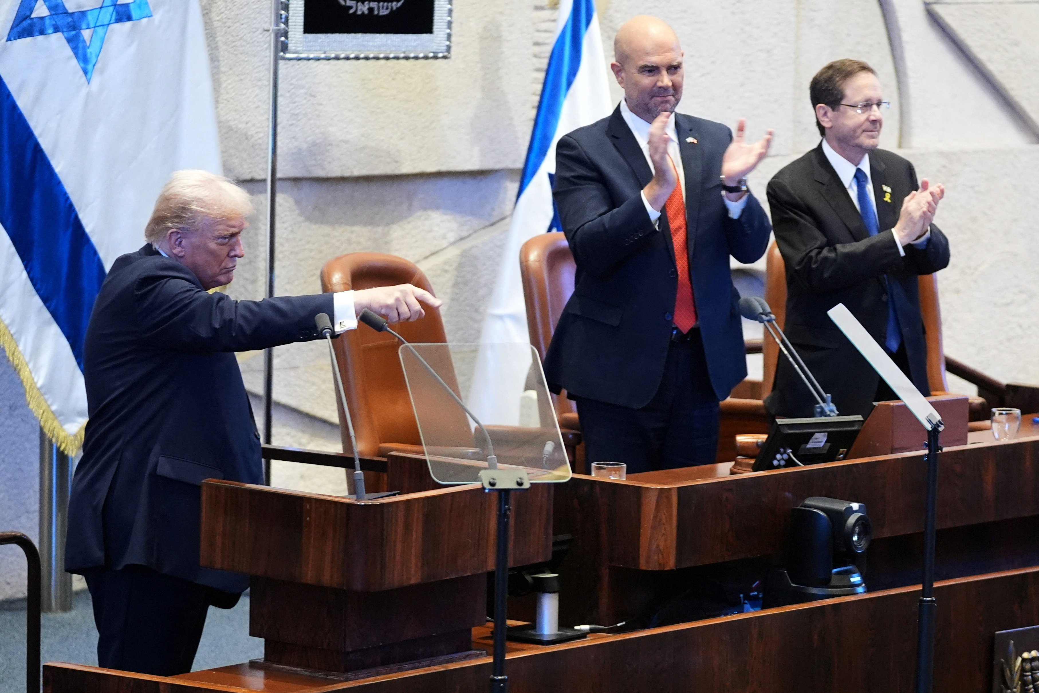 President Donald Trump gestures after speaking to the Knesset, Israel's parliament, Monday, Oct. 13, 2025, in Jerusalem, as Speaker Amir Ohana and Israel's President Isaac Herzog