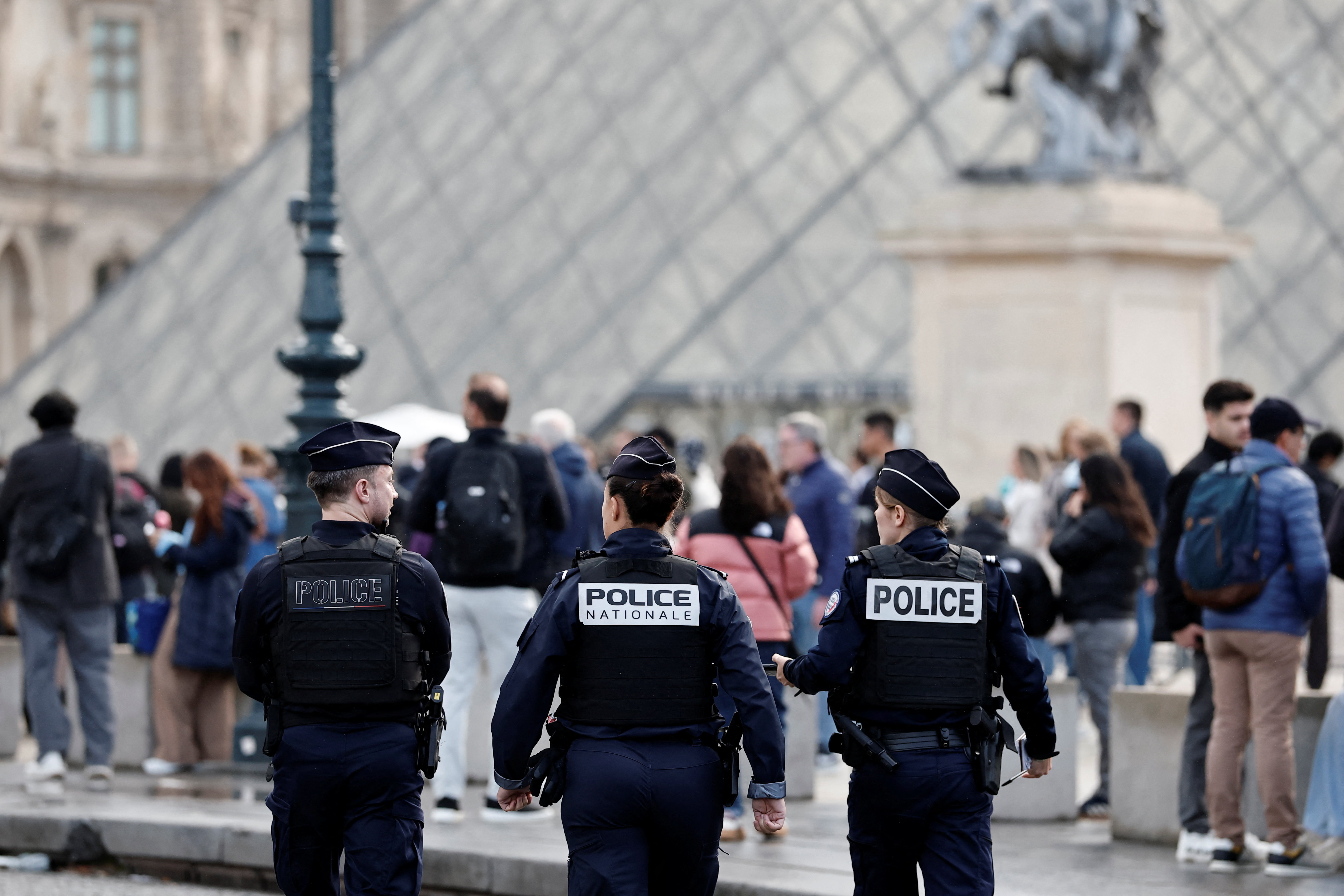 French police walk near the glass Pyramid of the Louvre Museum as the museum remains closed the day after a spectacular jewel heist by thieves who broke into the landmark by using a crane and smashing an upstairs window