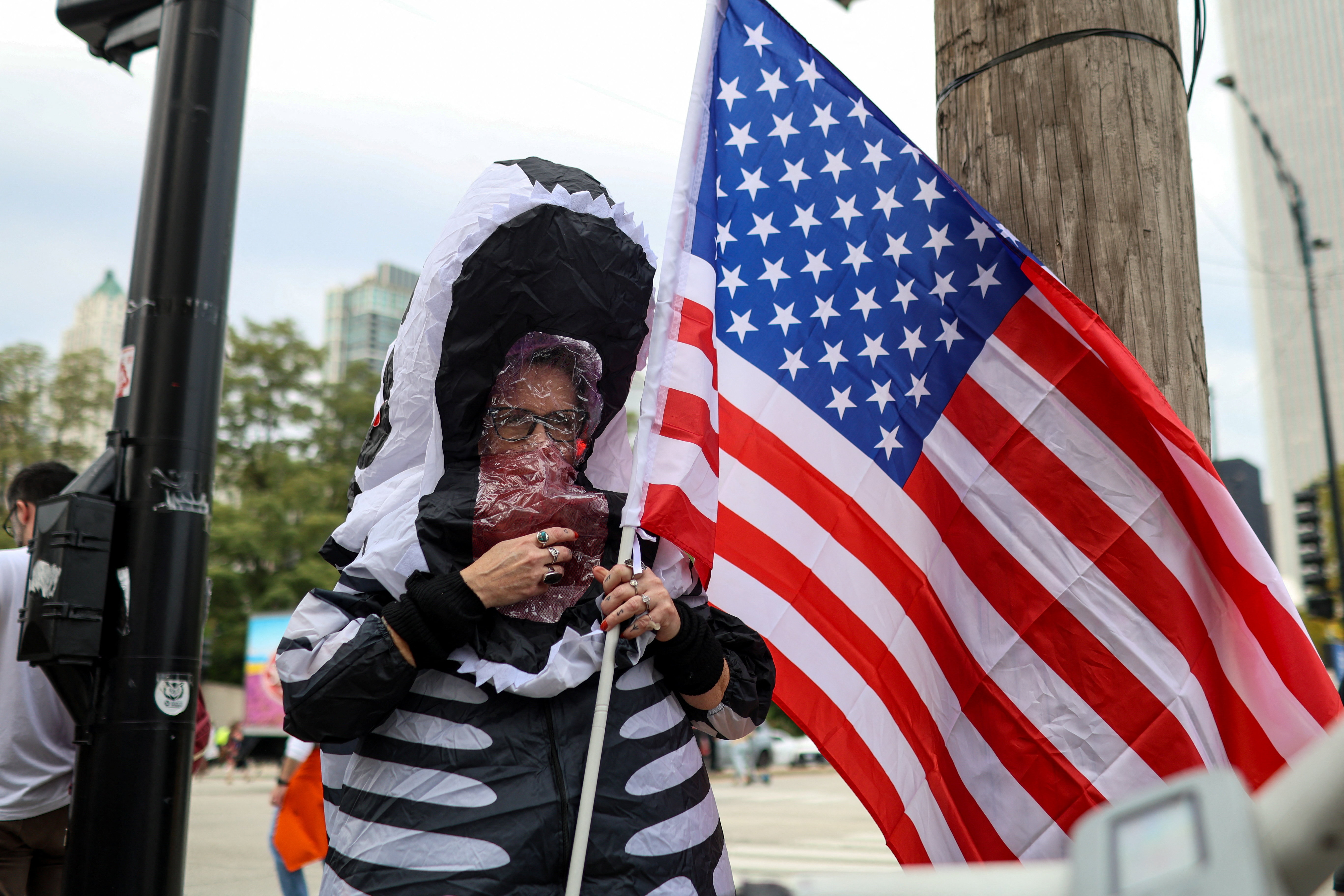 A demonstrator wearing an inflatable costume holds a U.S. flag on the day of a "No Kings" protest against U.S. President Donald Trump's policies, in Chicago, Illinois, U.S., October 18, 2025. REUTERS/Jim Vondruska