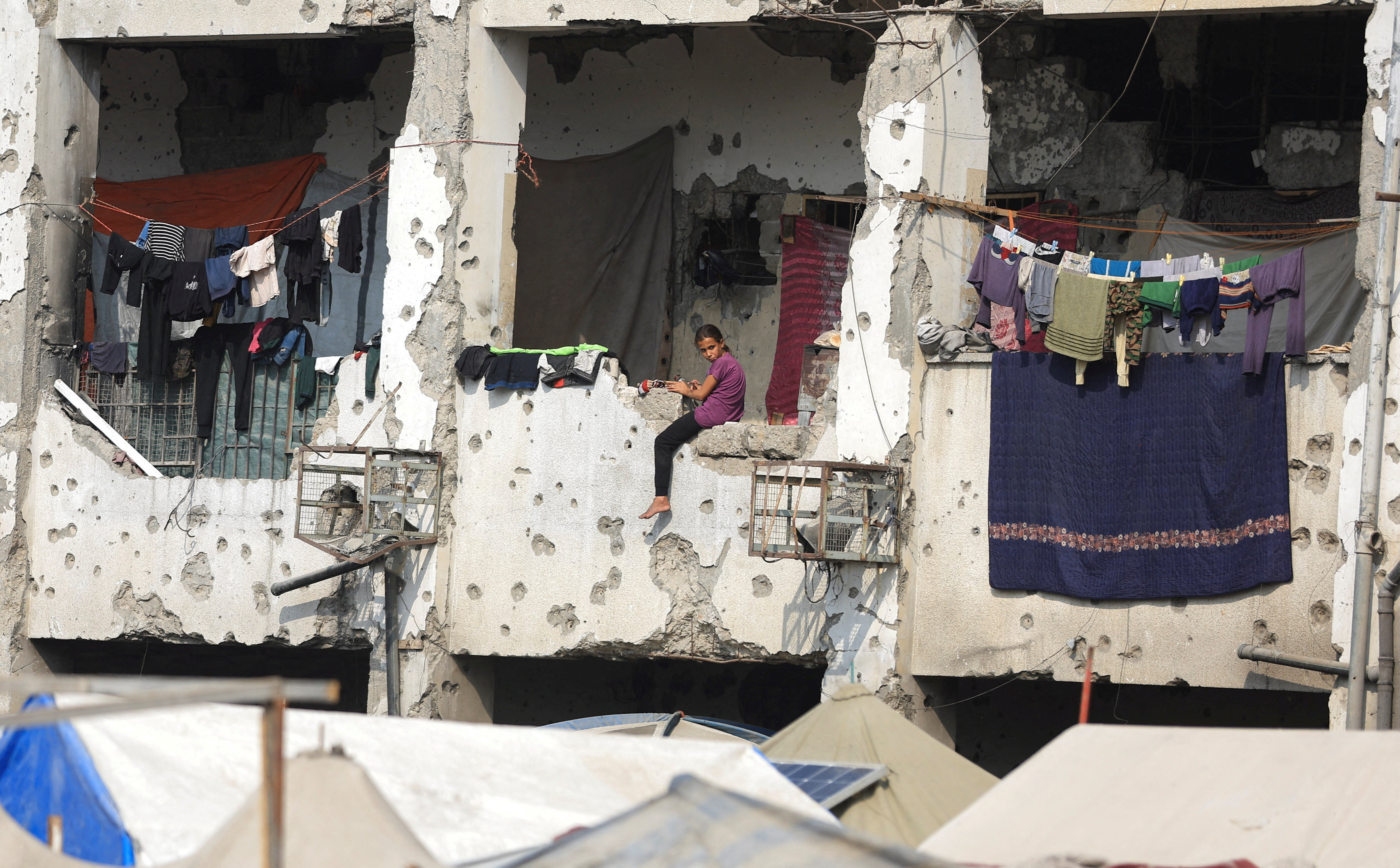 A displaced Palestinian girl sits on a wall of a damaged school where she has taken shelter, during a ceasefire between Israel and Hamas, in Gaza City, November 11, 2025. REUTERS/Dawoud Abu Alkas     TPX IMAGES OF THE DAY