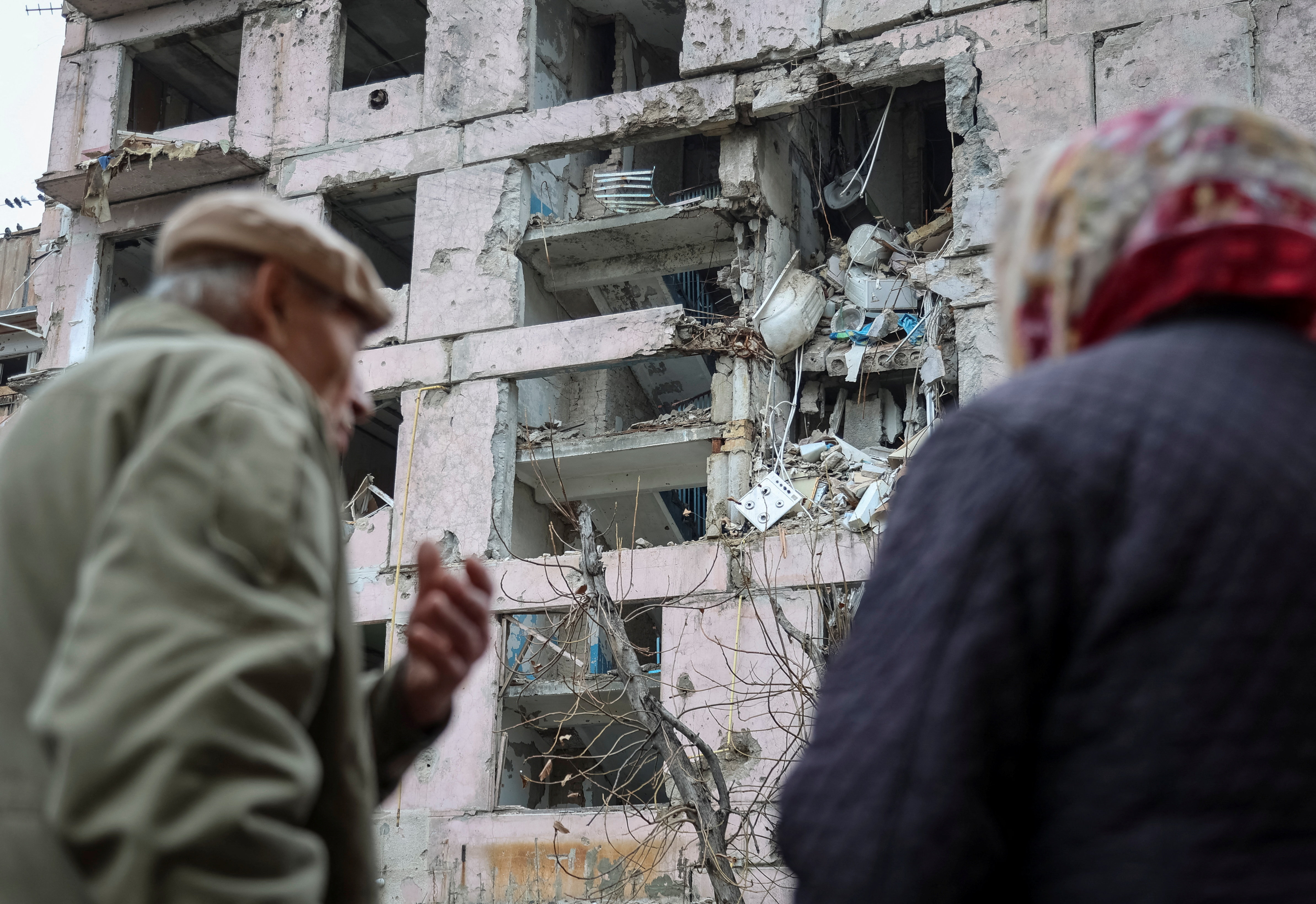 Residents stand near an apartment building hit during the Russian military strike, amid Russia's attack on Ukraine, in the frontline town of Huliaipole in Zaporizhzhia region, Ukraine November 11, 2025.