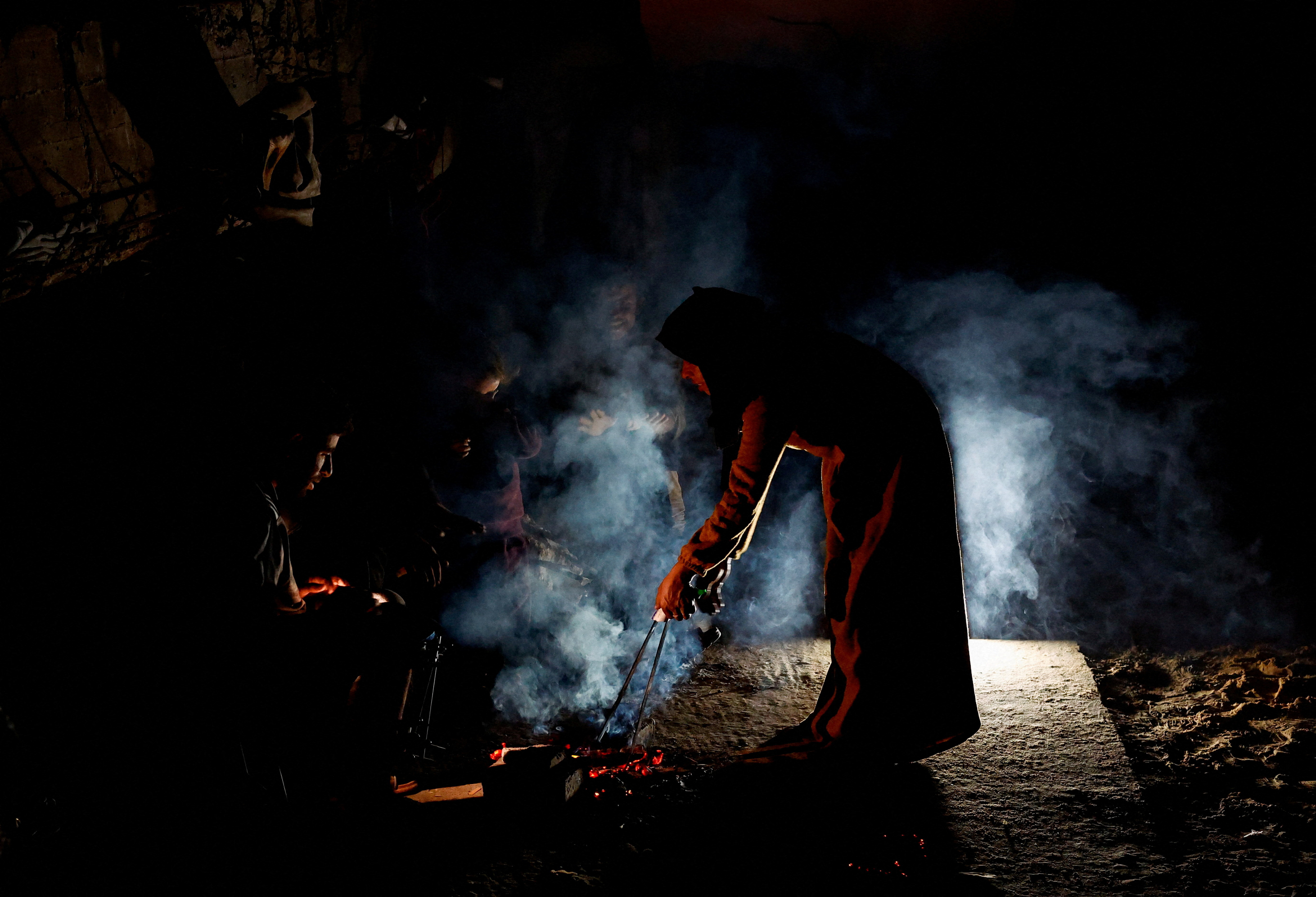 Palestinians gather by a fire, amid a ceasefire between Israel and Hamas, in the northern Gaza Strip November 19, 2025. REUTERS/Mahmoud Issa     TPX IMAGES OF THE DAY