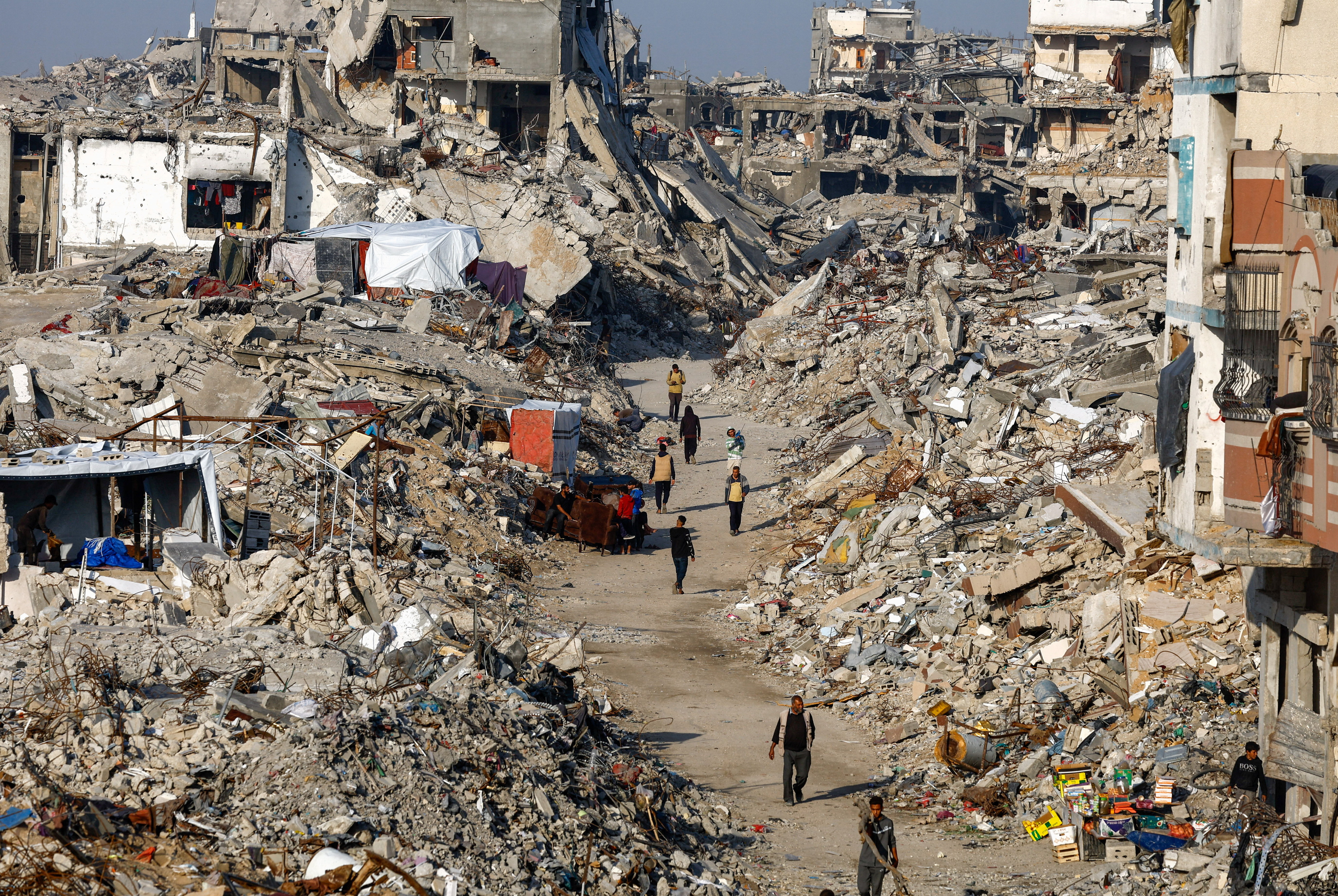 Palestinians walk among piles of rubble and damaged buildings, amid a ceasefire between Israel and Hamas, in the northern Gaza Strip November 19, 2025. REUTERS/Mahmoud Issa