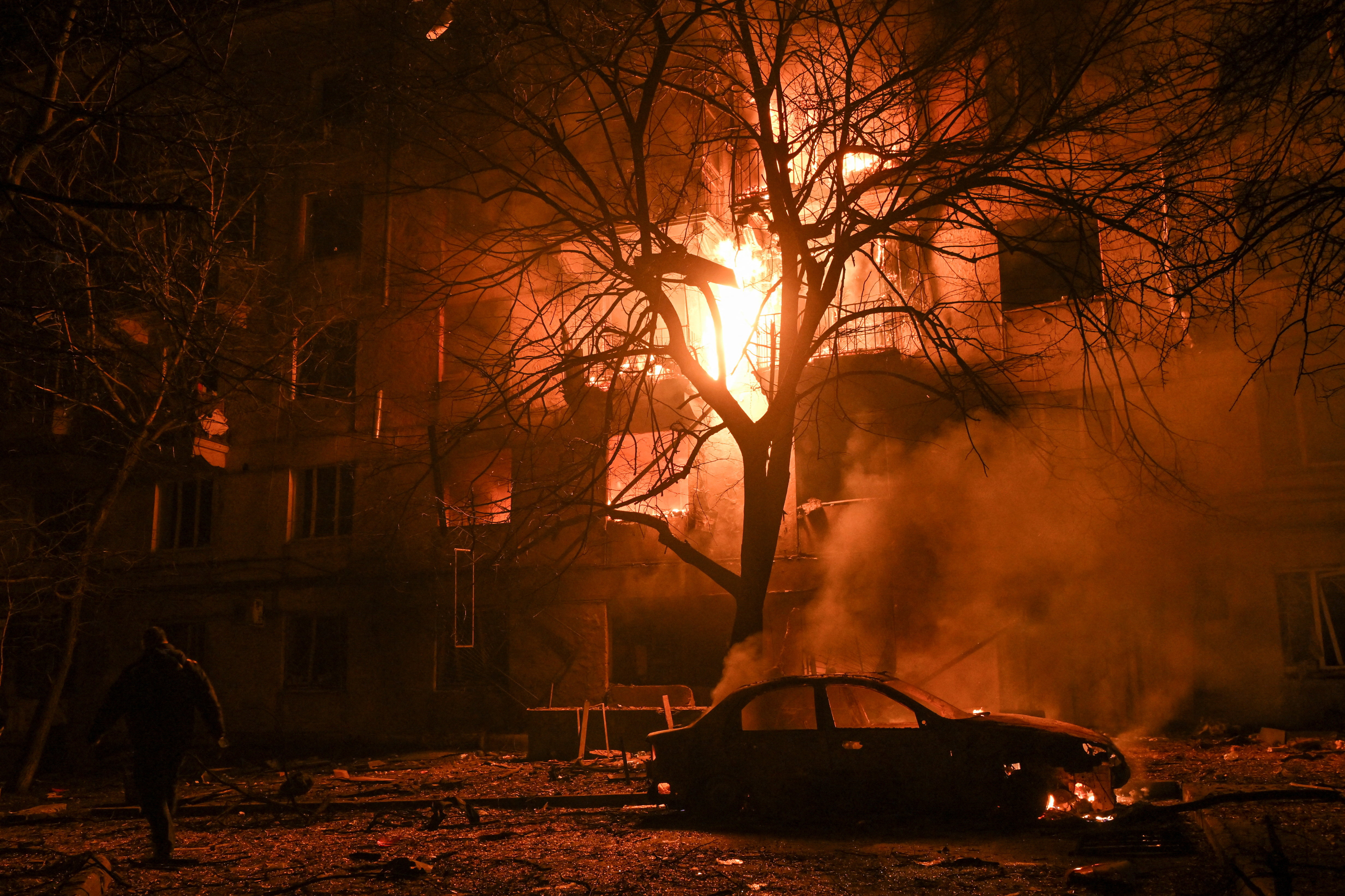 A resident walks in front of a burning apartment building which was damaged during an evening Russian drone strike, amid Russia's attack on Ukraine, in Zaporizhzhia, Ukraine November 25, 2025. REUTERS/Stringer