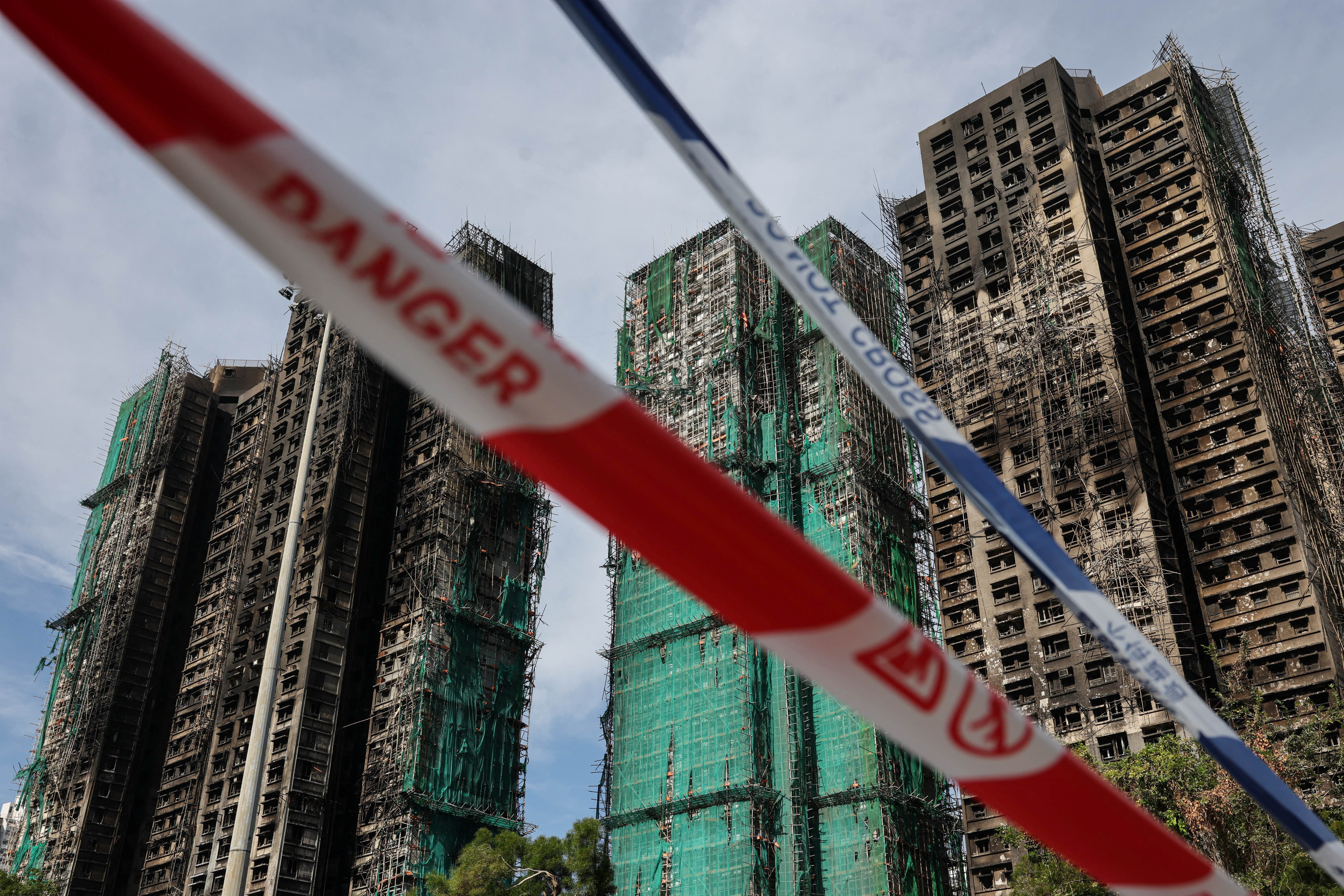 Police cordons are placed at the scene of the Wang Fuk Court housing estate fire as mourners pay tribute to the victims, in Tai Po, Hong Kong, China, November 28, 2025. REUTERS/Tyrone Siu