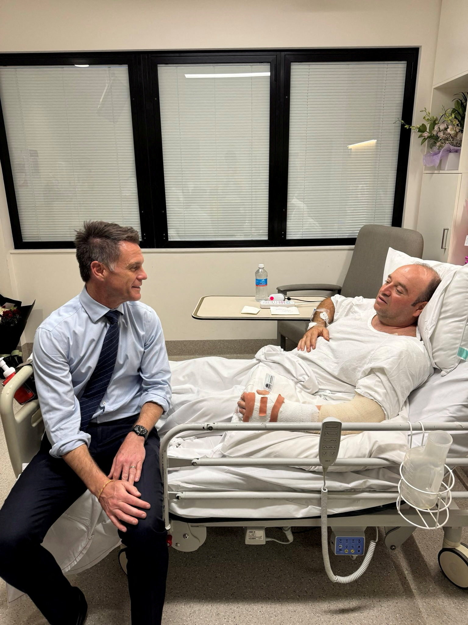 New South Wales Premier Chris Minns visits Ahmed al Ahmed, who was identified on social media as the bystander who hid behind parked cars and seized a rifle from one of the gunmen during the deadly shooting at Bondi Beach  @ChrisMinnsMP via X/via REUTERS