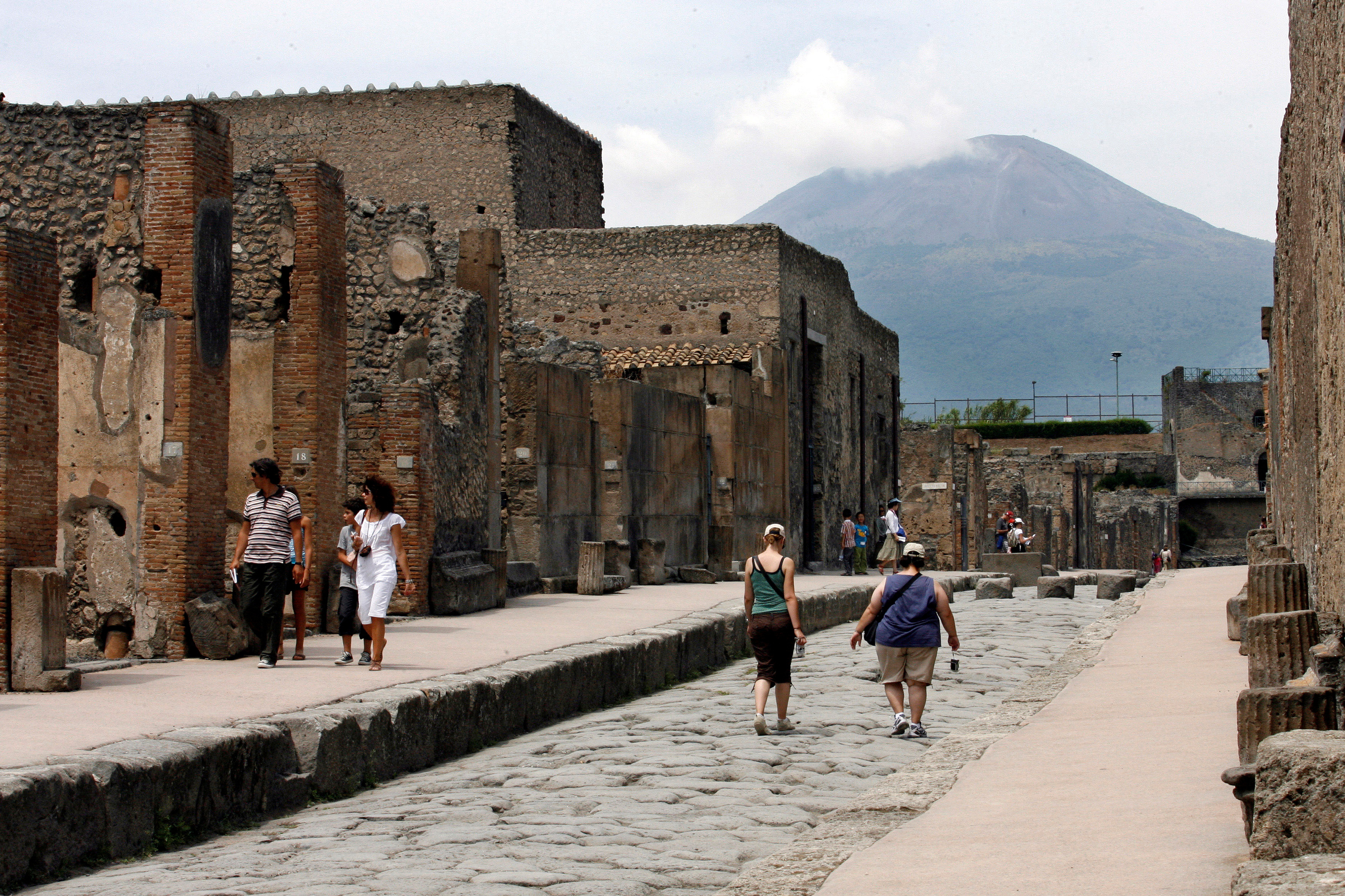 FILE PHOTO: Visitors walk in Pompeii, the famous city next to Naples which was destroyed in AD 79 by the eruption of Mount Vesuvius seen in the background, July 17, 2008.