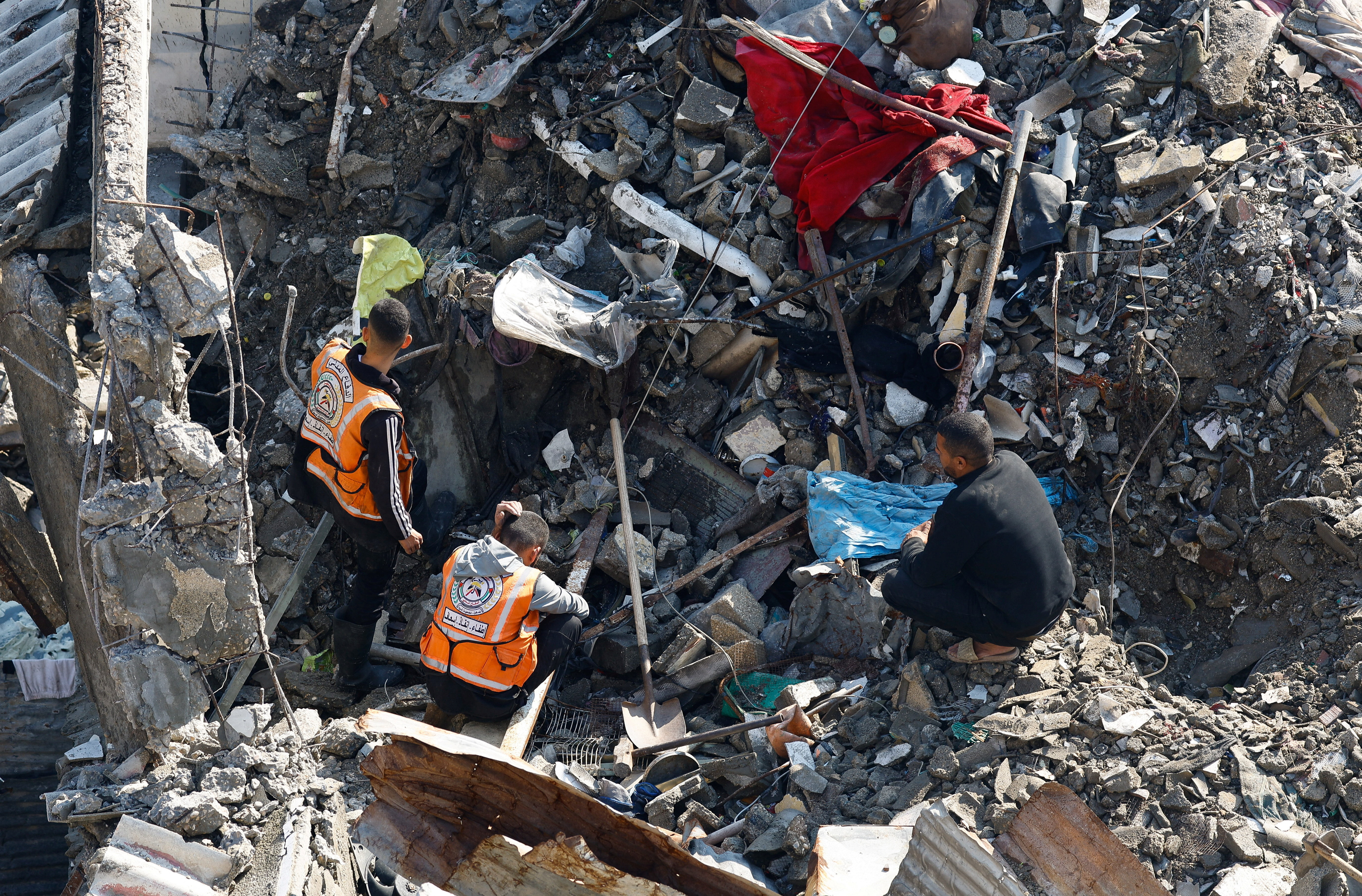 A man watches as members of the Palestinian Civil Defence participate in a search and rescue operation at the site of a house that was partially destroyed during the war and collapsed on Tuesday, at Shati refugee camp in Gaza City