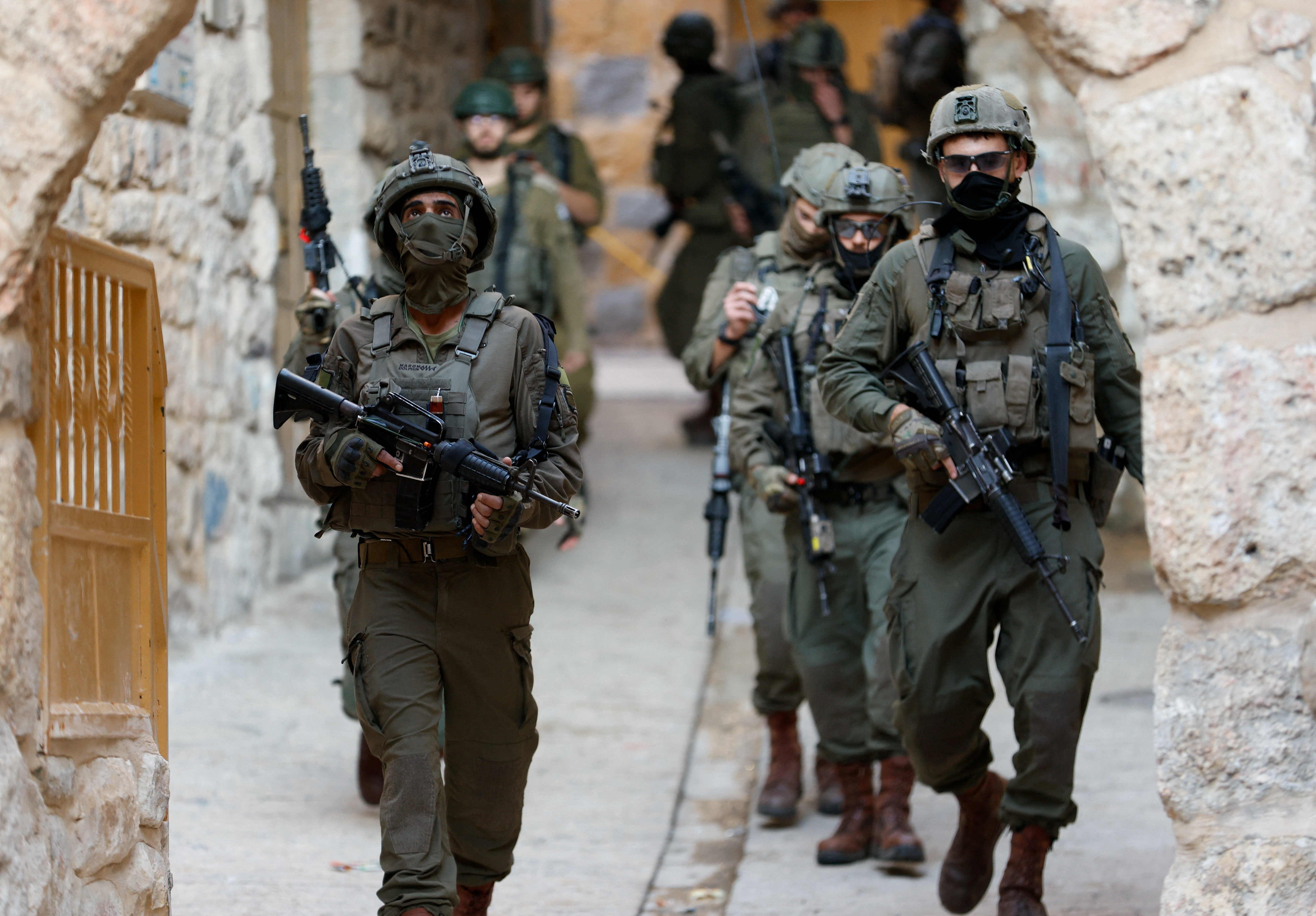 Israeli soldiers carrying weapons walk during a weekly settlers' tour in Hebron, in the Israeli-occupied West Bank