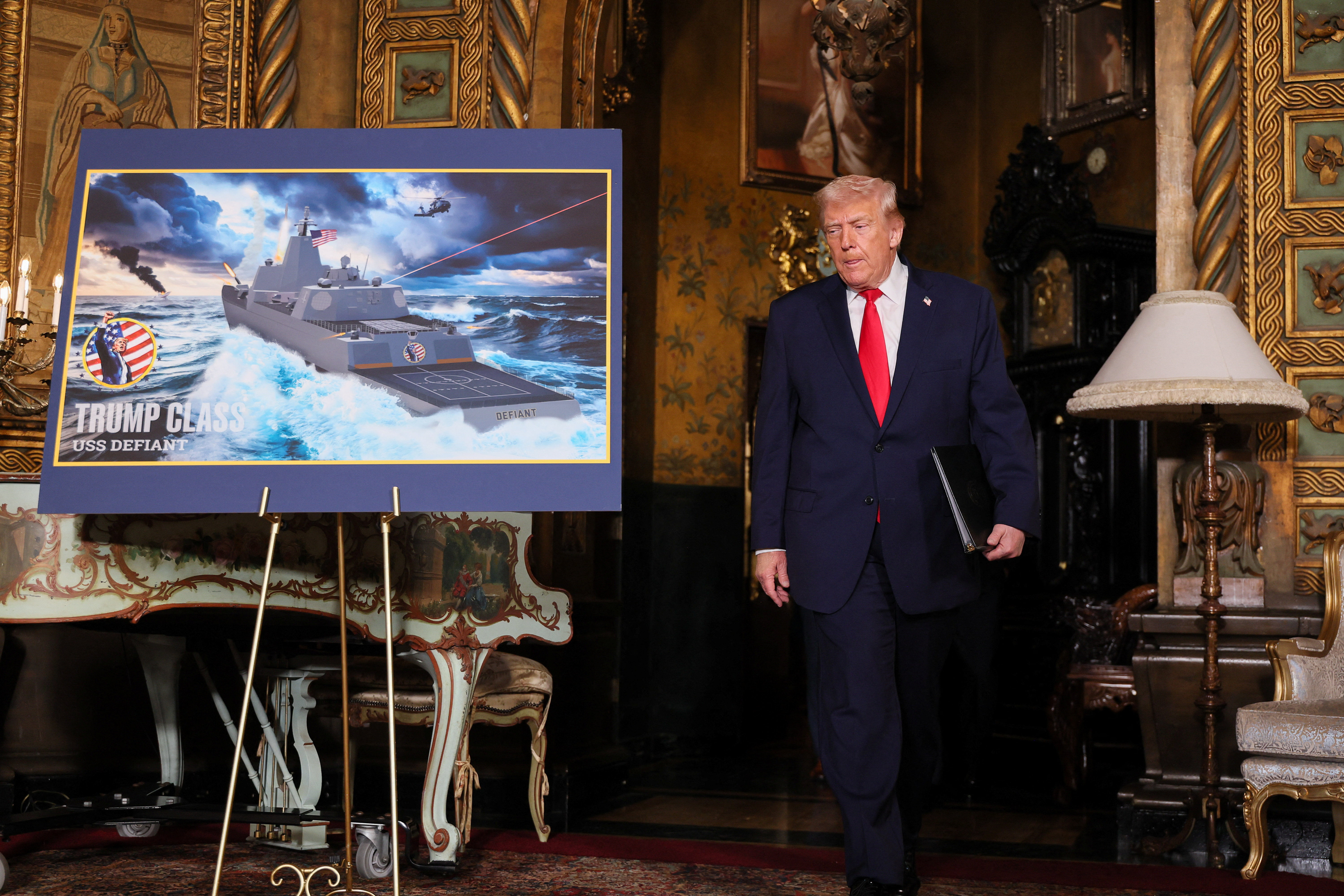 U.S. President Donald Trump walks past a rendering of the 'Trump Class' USS Deifant, at Mar-a-lago in Palm Beach, Florida, U.S., December 22, 2025.