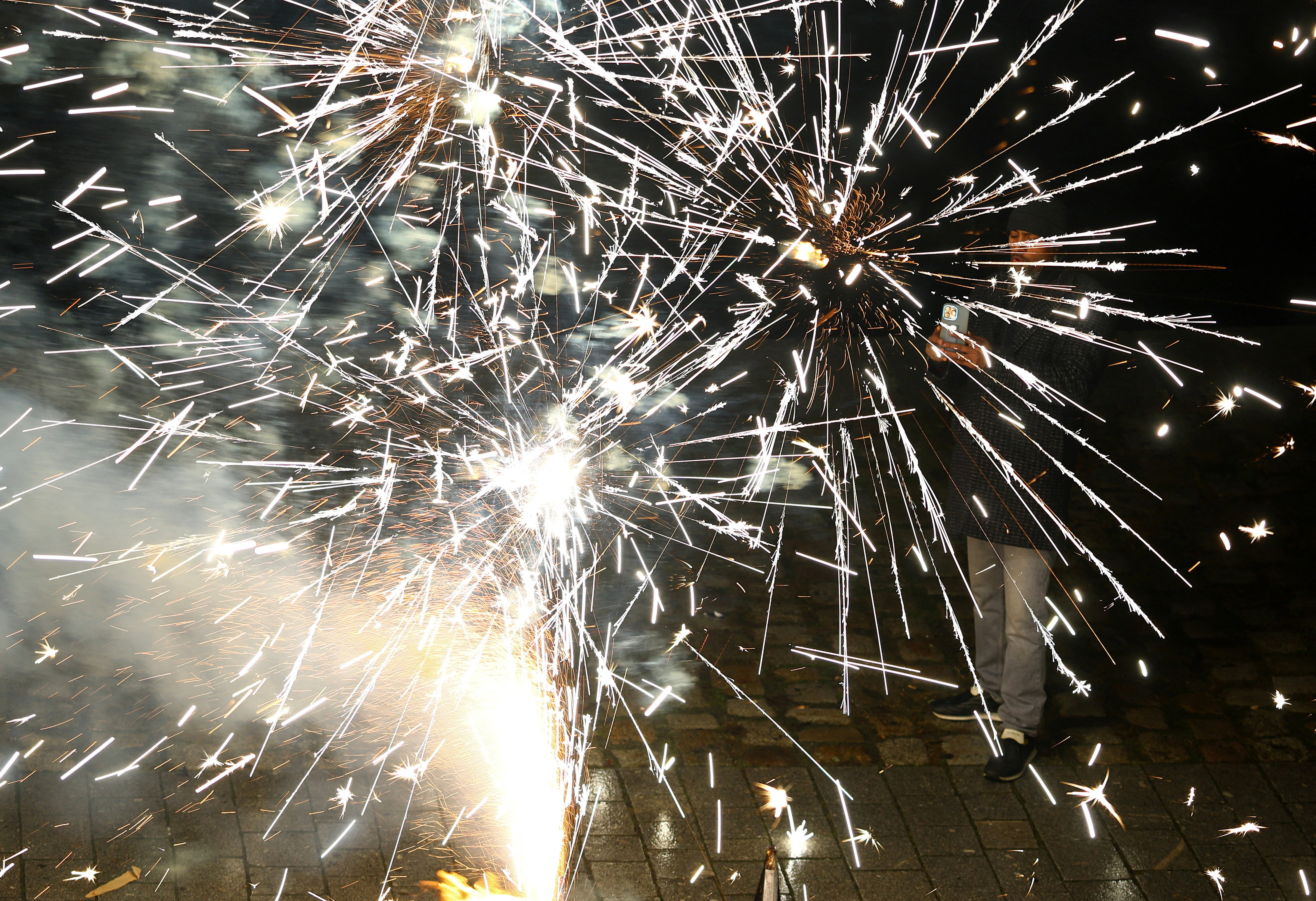 A person uses a smartphone as fireworks explode to mark the New Year's celebrations in central Berlin, Germany, January 1, 2026.REUTERS/Lisi Niesner