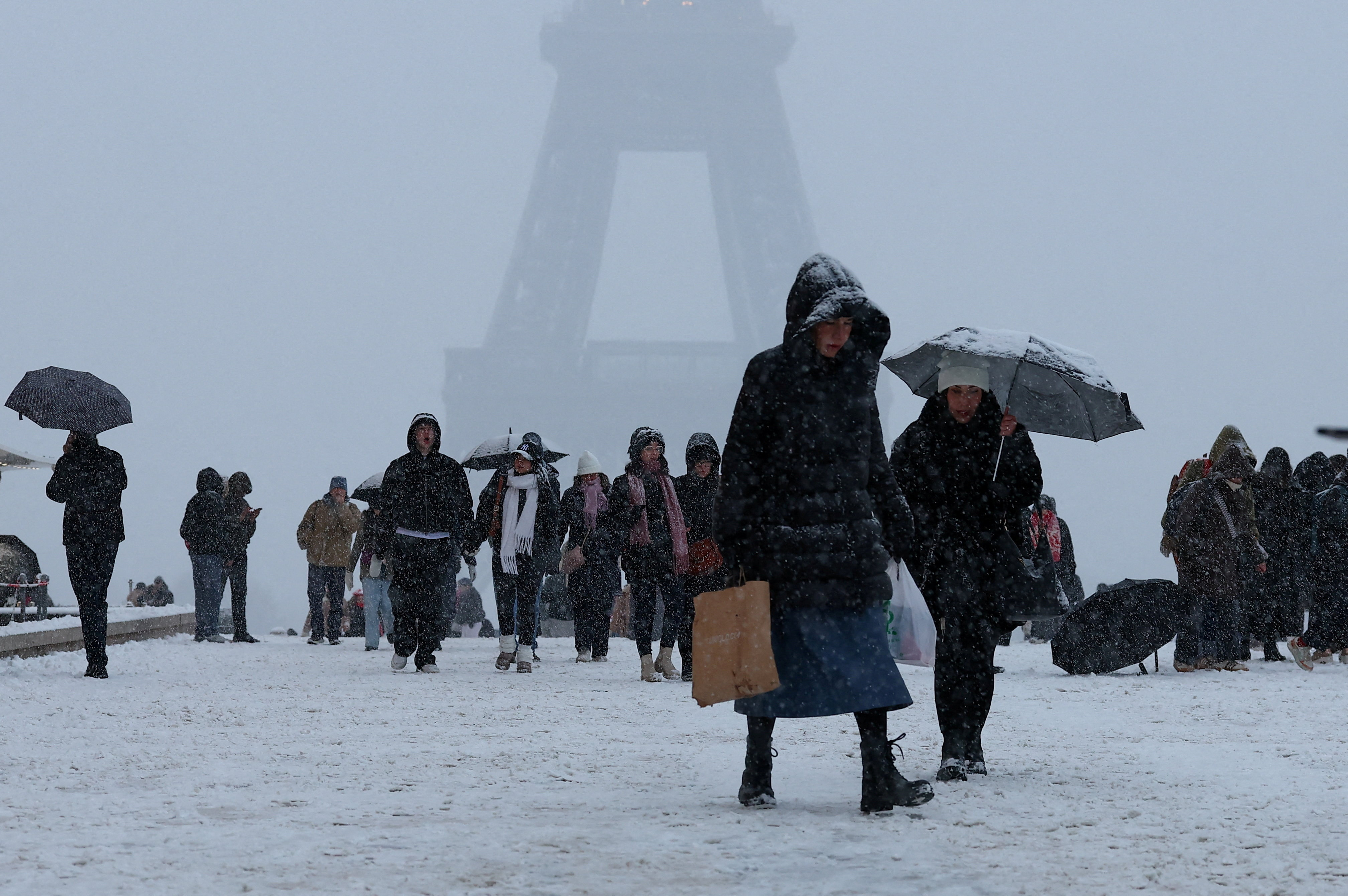 People walk in the snow-covered Trocadero square near the Eiffel Tower, as winter weather with snow and cold temperatures hits a large part of the country, in Paris, France, January 5, 2026. REUTERS/Gonzalo Fuentes     TPX IMAGES OF THE DAY