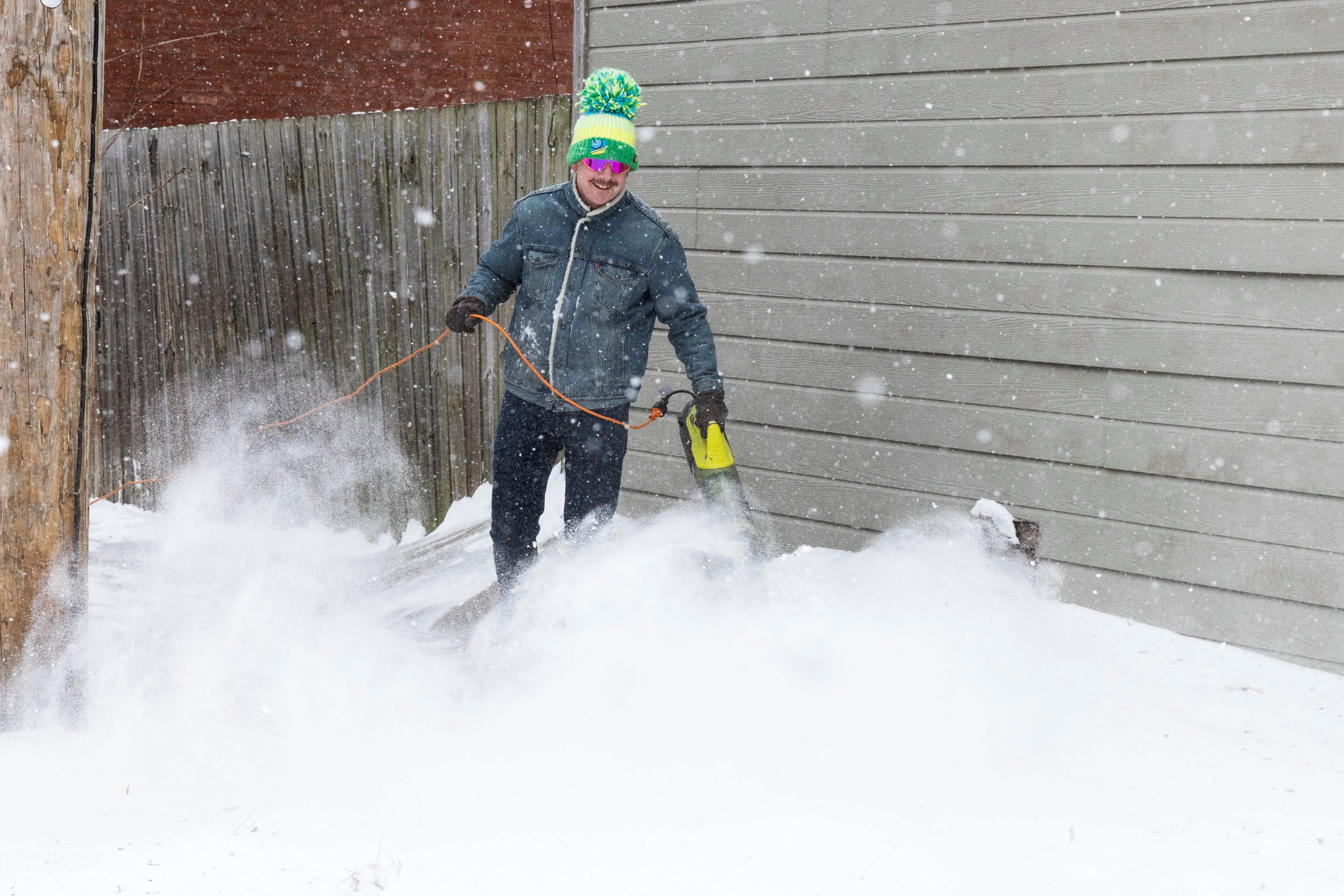A resident uses a snowblower to clear accumulated snow from a sidewalk as snowfall continues across St. Louis, Missouri, U.S., January 24, 2026. REUTERS/Lawrence Bryant