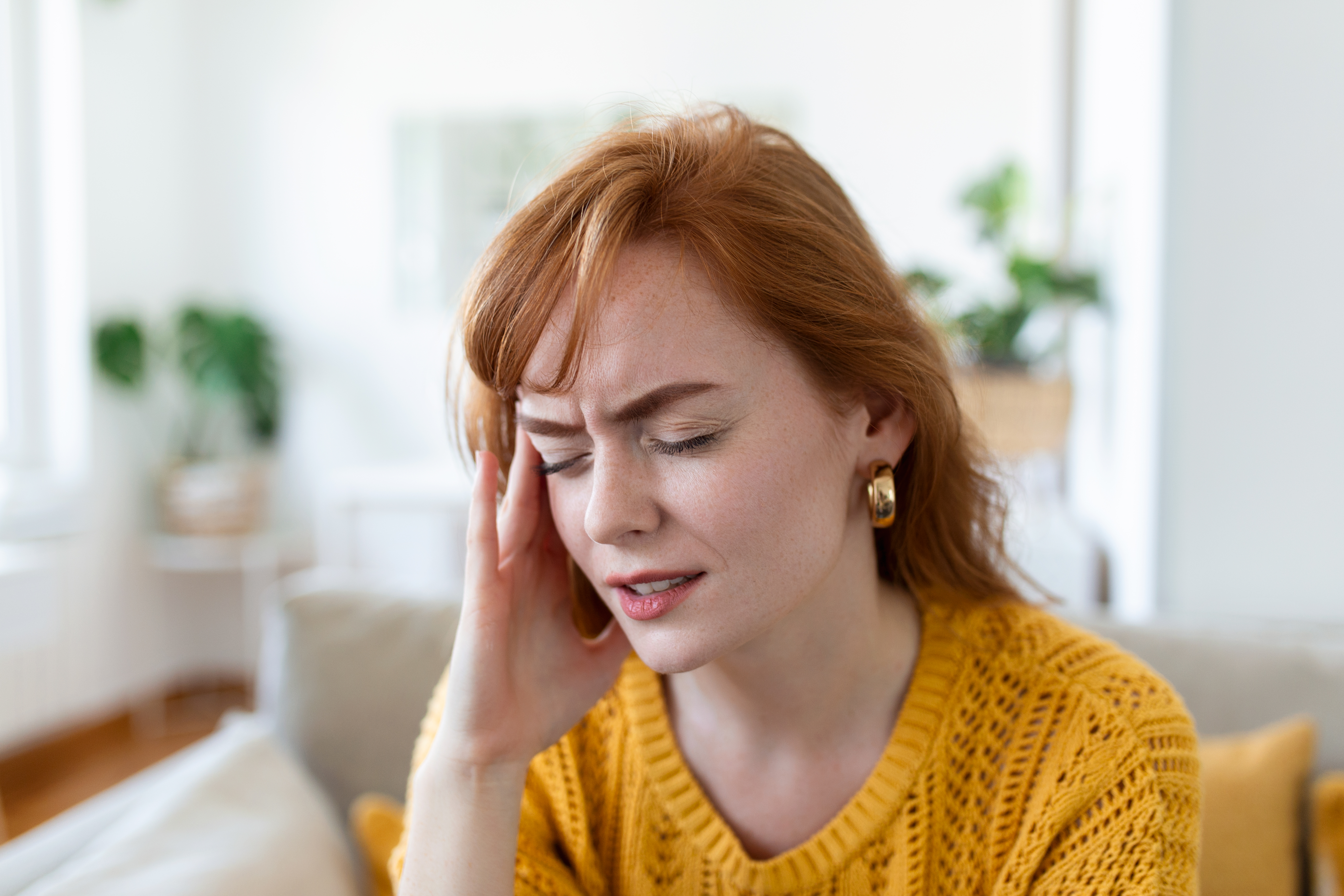 Closeup view frown face of woman feeling strong headache touch temple to reduce severe pain, suffering from panic attack in office, migraine overworked person or hangover alcohol abuse concept