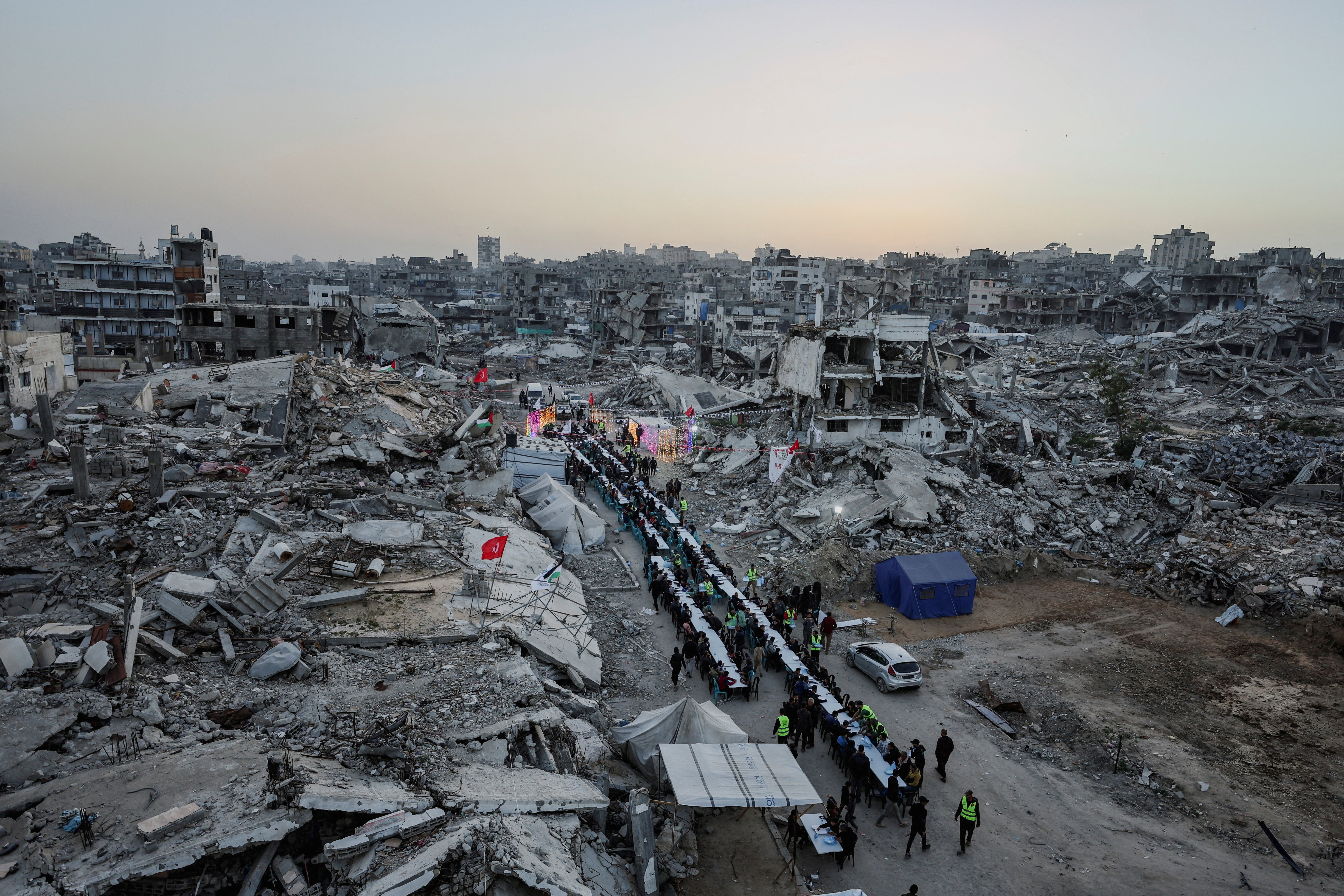 Palestinians gather to break their fast by eating Iftar meals on the first day of the holy month of Ramadan, near the rubble of residential buildings destroyed during the two-year Israeli offensive