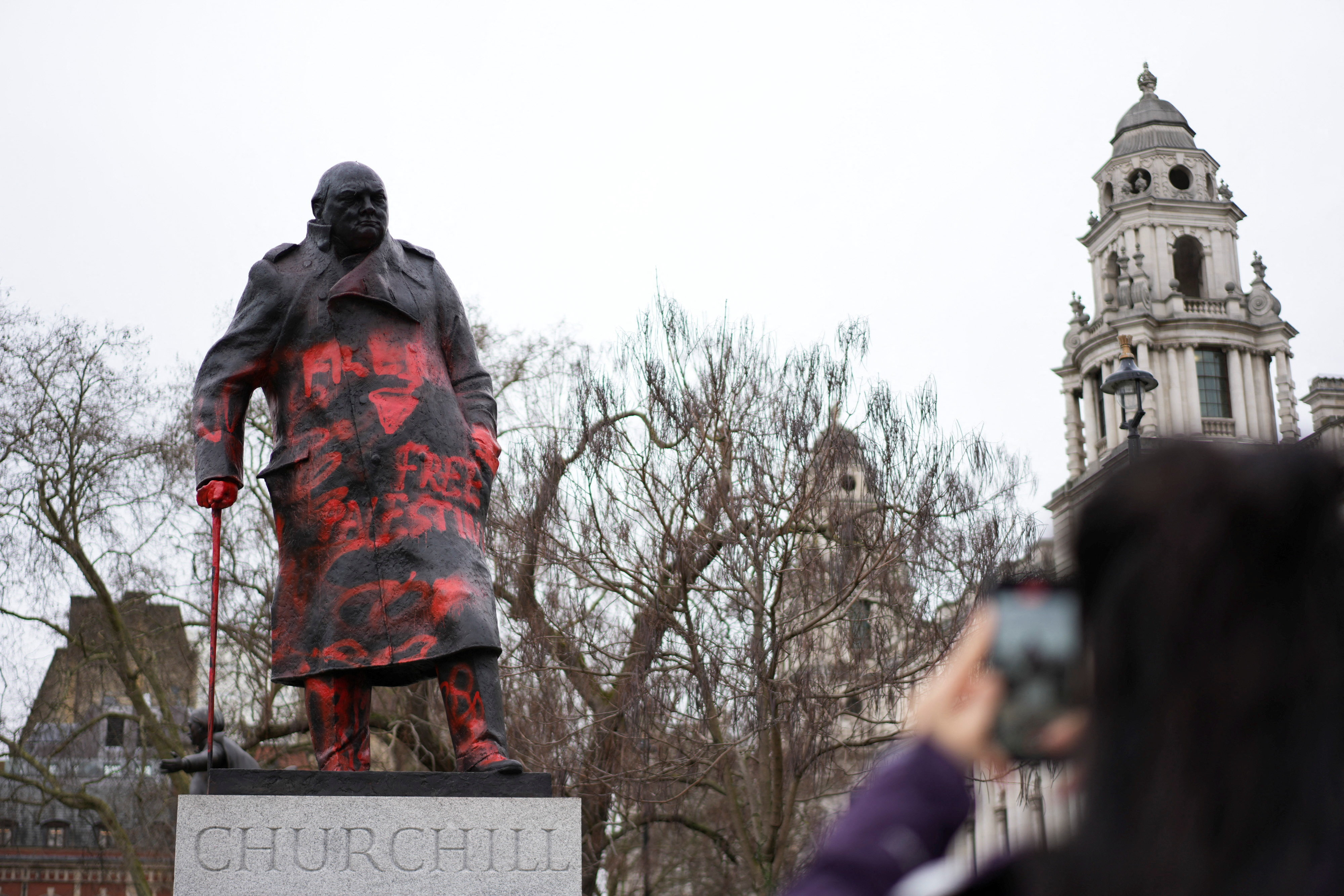 A woman takes photos of the statue of Sir Winston Churchill in Parliament Square, which has been defaced overnight with red paint and the words 'Free Palestine', in London, Britain, February 27, 2026.