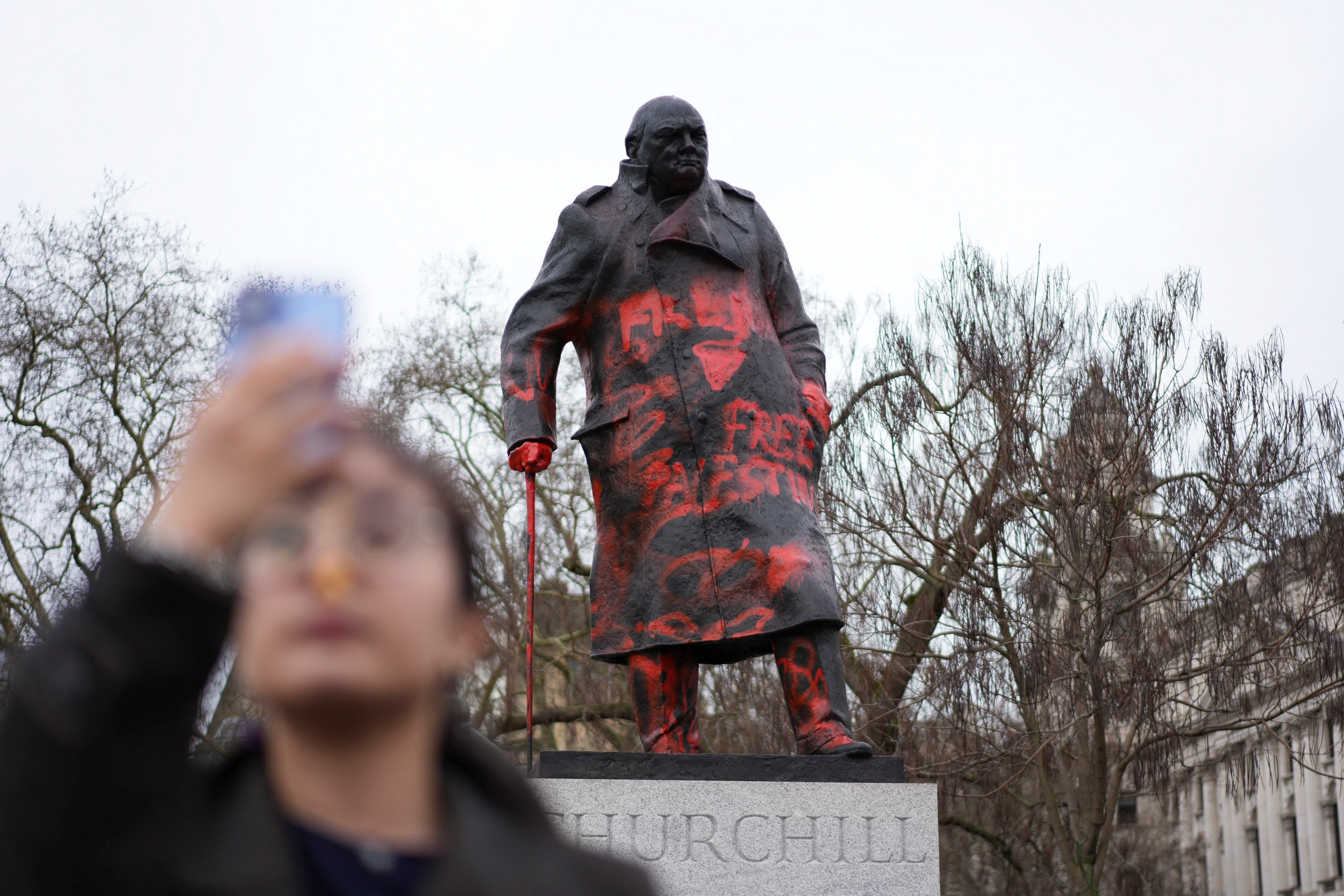 A woman takes photos next to the statue of Sir Winston Churchill, which was defaced overnight with red paint and the words "Free Palestine", in Parliament Square, London, Britain, February 27, 2026.
