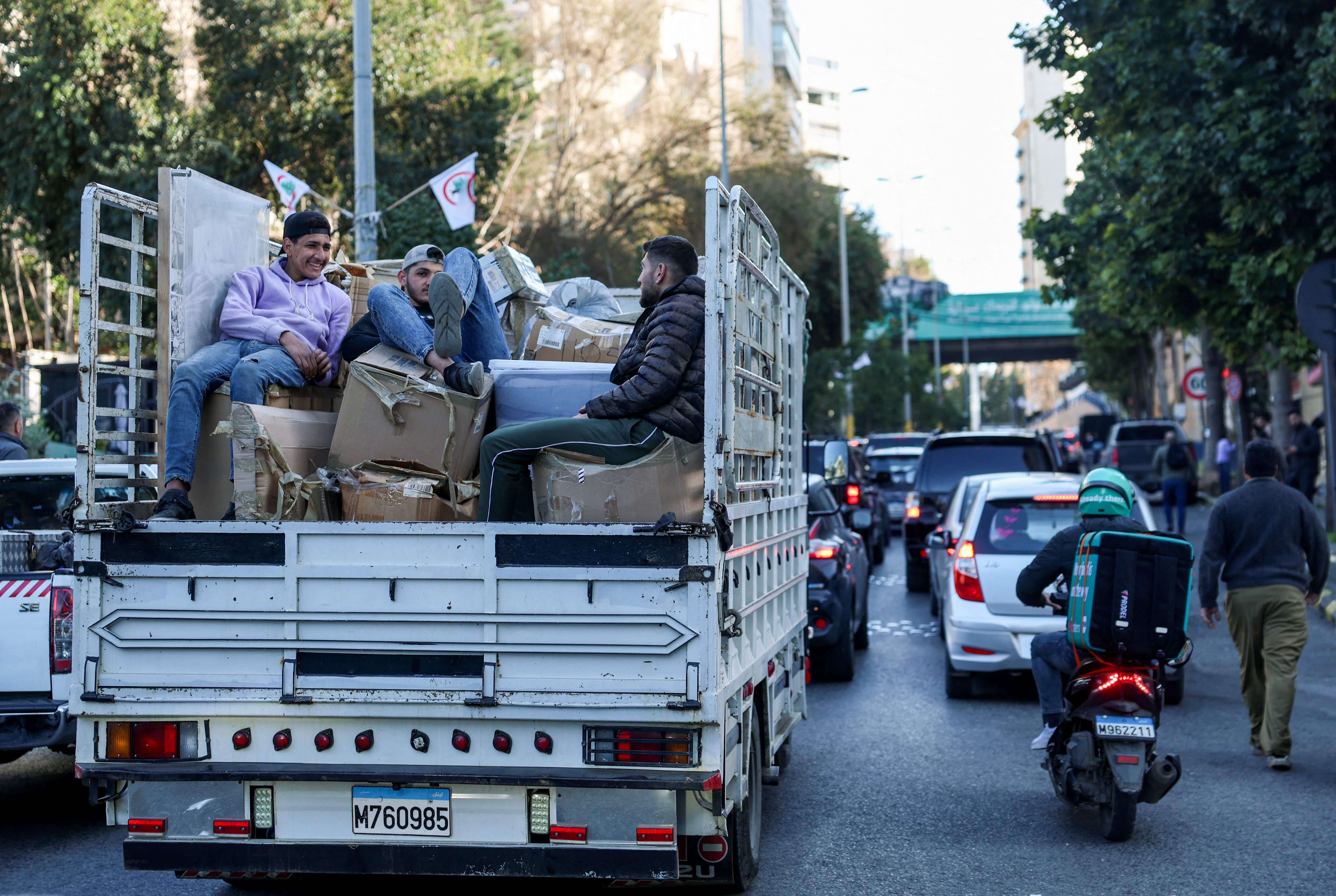 People sit on the back of a vehicle as they wait in traffic, after the Israel's military issued evacuation orders of entire neighborhoods in Beirut's southern suburb