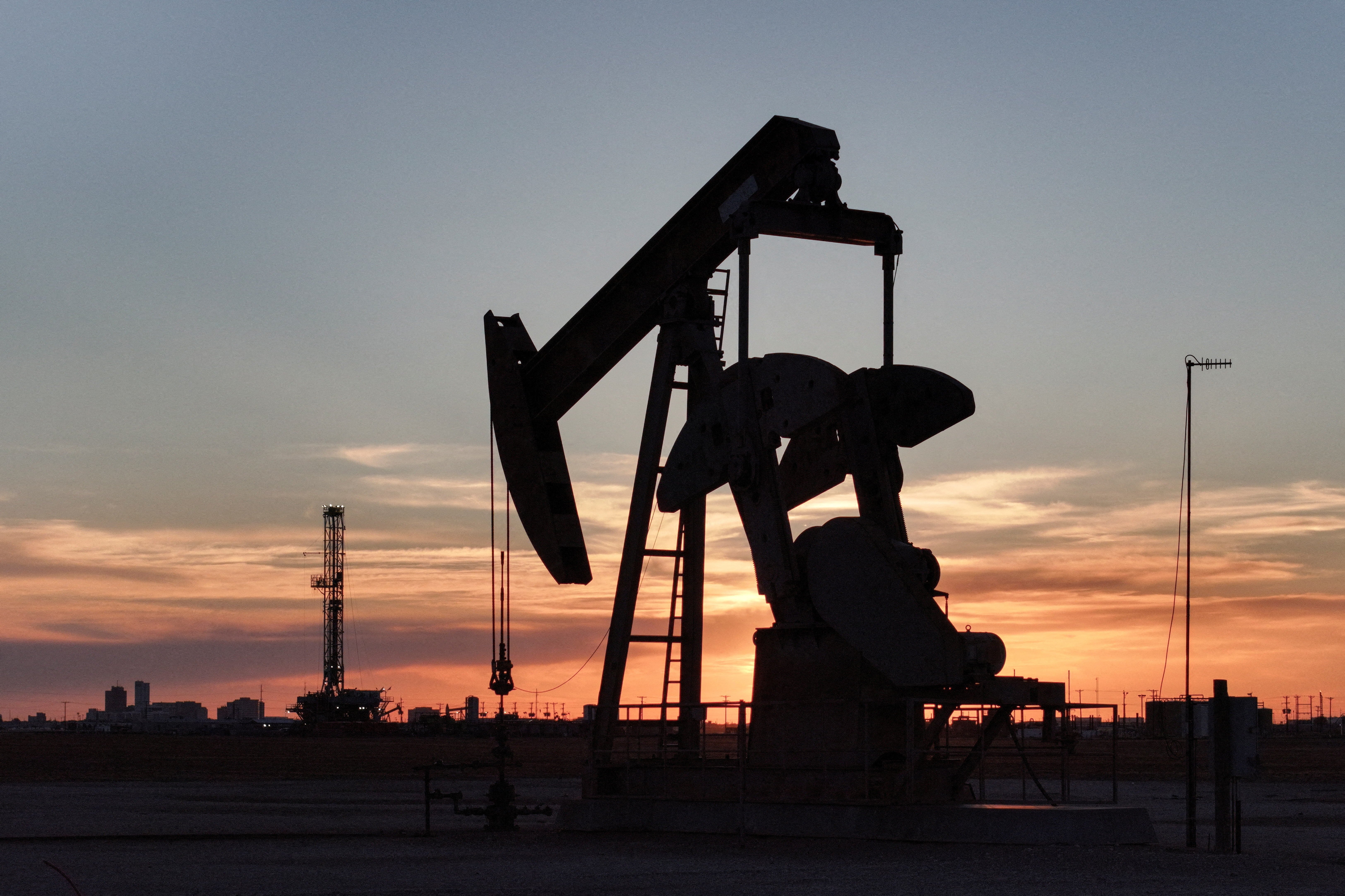 FILE PHOTO: A drone view of a pump jack and drilling rig south of Midland, Texas, U.S. June 11, 2025. REUTERS/Eli Hartman/File Photo
