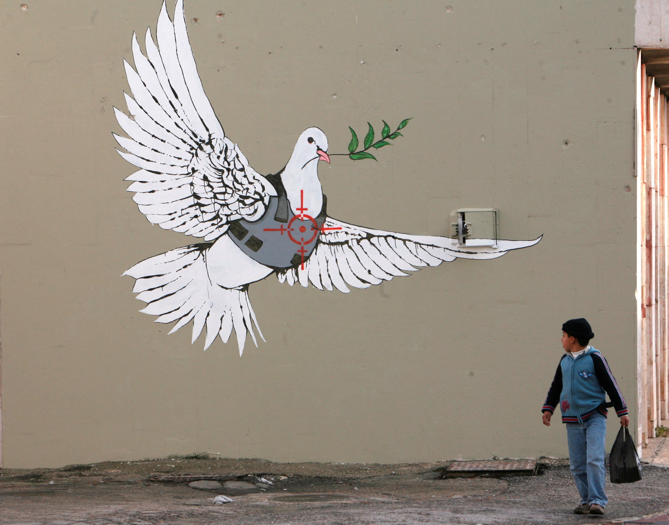 FILE PHOTO: A Palestinian boy looks at one of six new images painted by British street artist Banksy as part of a Christmas exhibition in the West Bank town of Bethlehem December 2, 2007. REUTERS/Ammar Awad