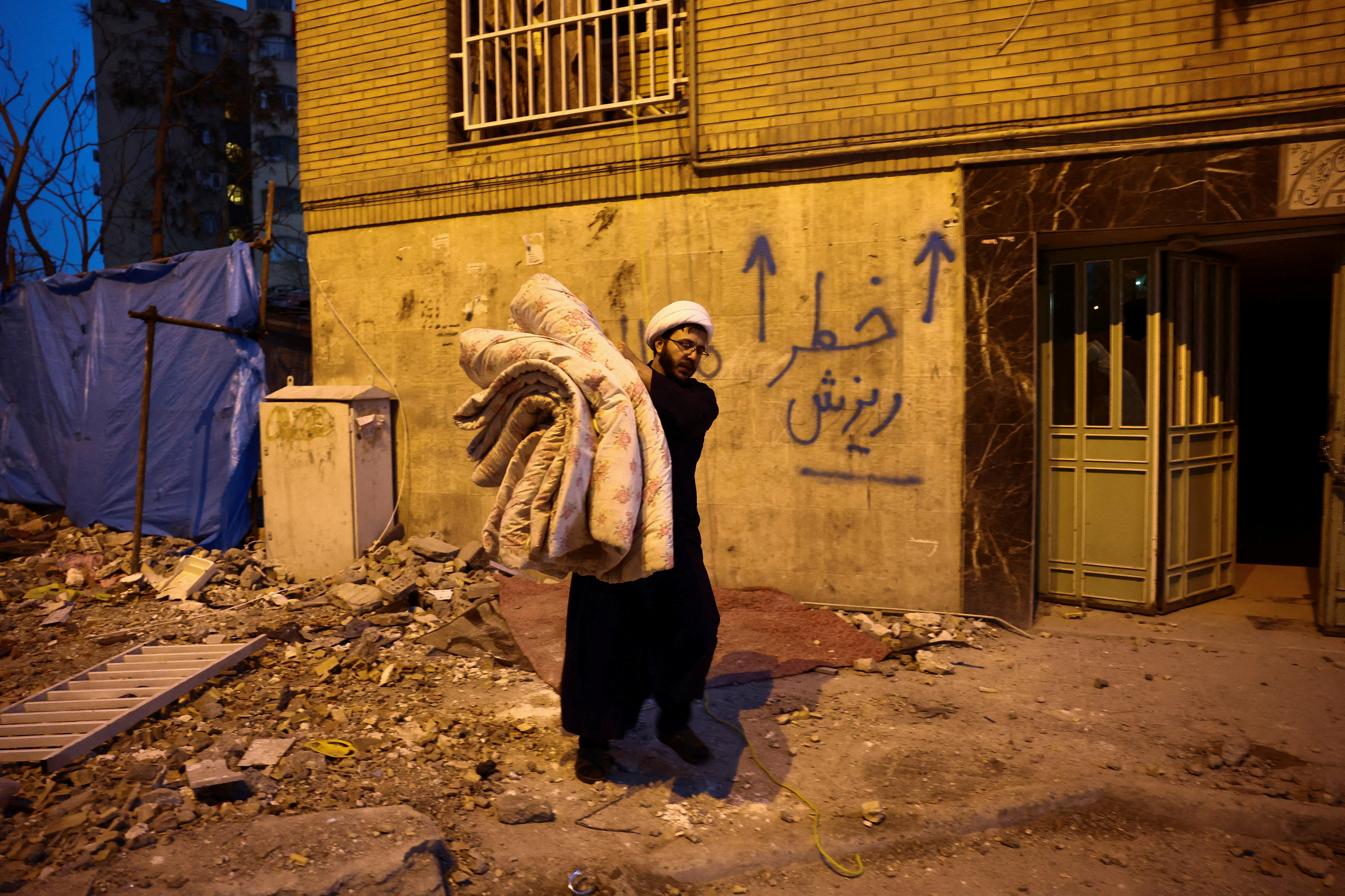 A volunteer carries belongings from one of the damaged houses, which was damaged in a strike, amid the U.S.-Israeli conflict with Iran, in Tehran, Iran, March 18, 2026