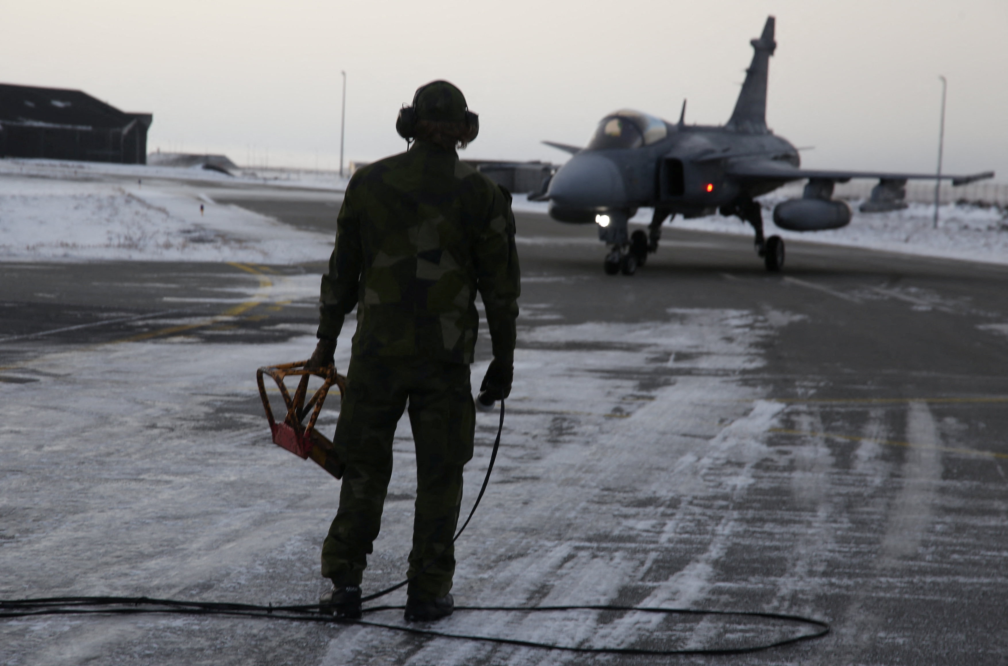 A Swedish ground crew member watches as a JAS 39 Gripen approaches on the tarmac at the air base in Keflavik, Iceland, March 3, 2026.