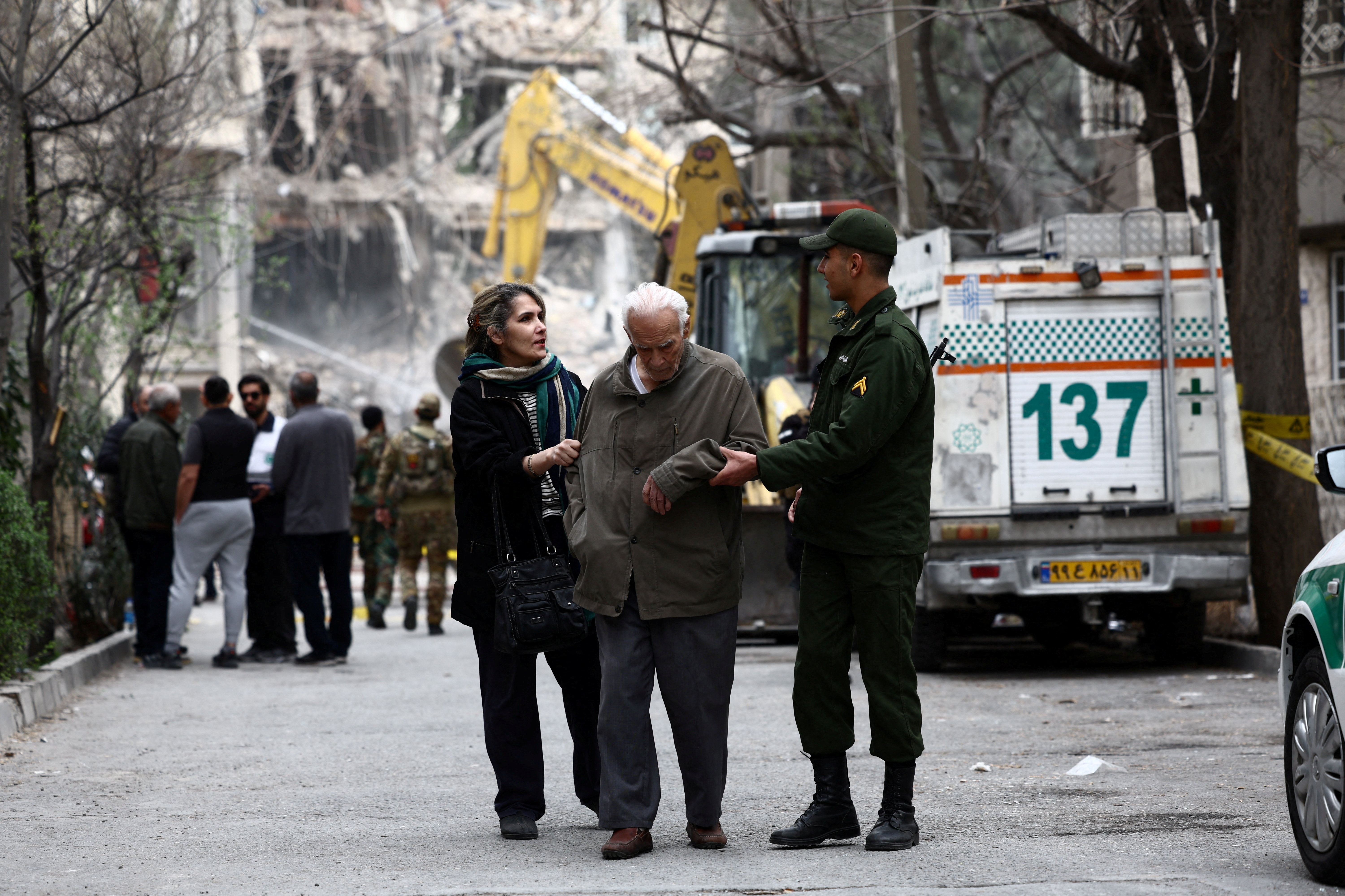 A soldier helps a man at the site of a strike on a residential building, amid the U.S.-Israeli conflict with Iran, in Tehran, Iran, March 23, 2026