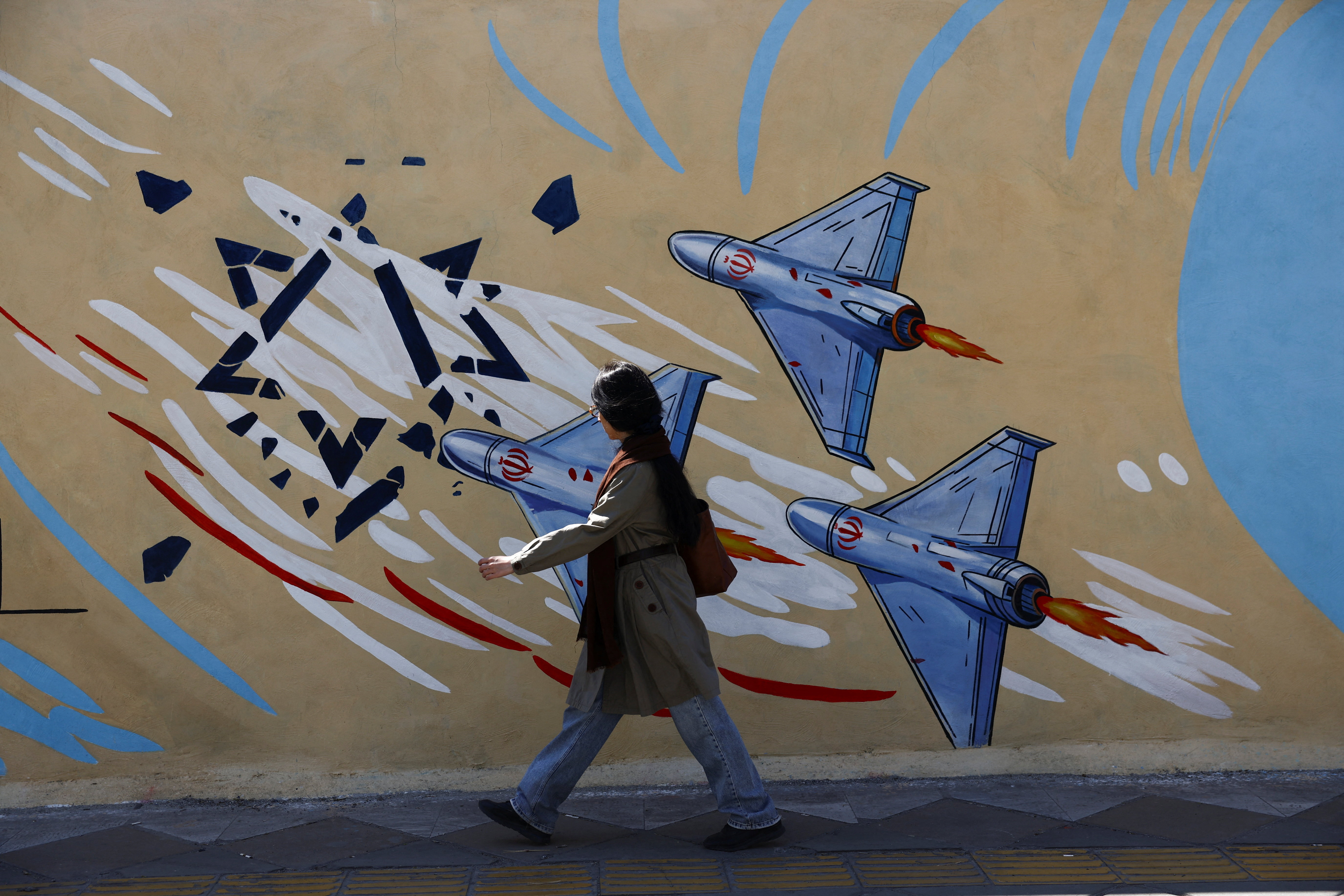 A woman walks next to an anti-Israeli mural on a street after U.S. President Donald Trump said that he had agreed to a two-week ceasefire with Iran, in Tehran, Iran, April 8, 2026.