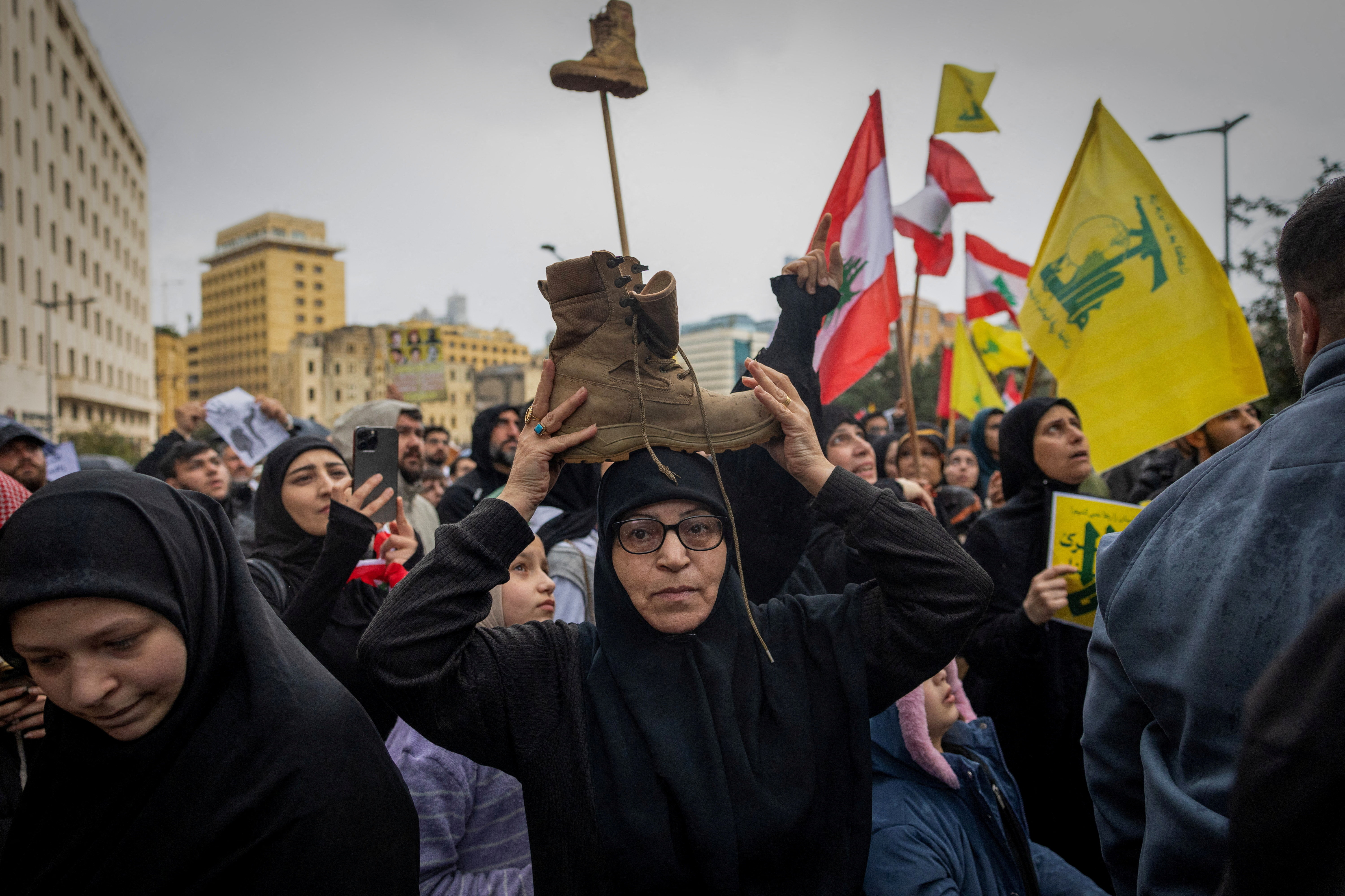 A woman places a symbolic boot on her head as a gesture of respect for a Lebanese fighter, as she takes part with demonstrators, including Hezbollah supporters, in a protest against the direct negotiation between the Israeli and Lebanese governments