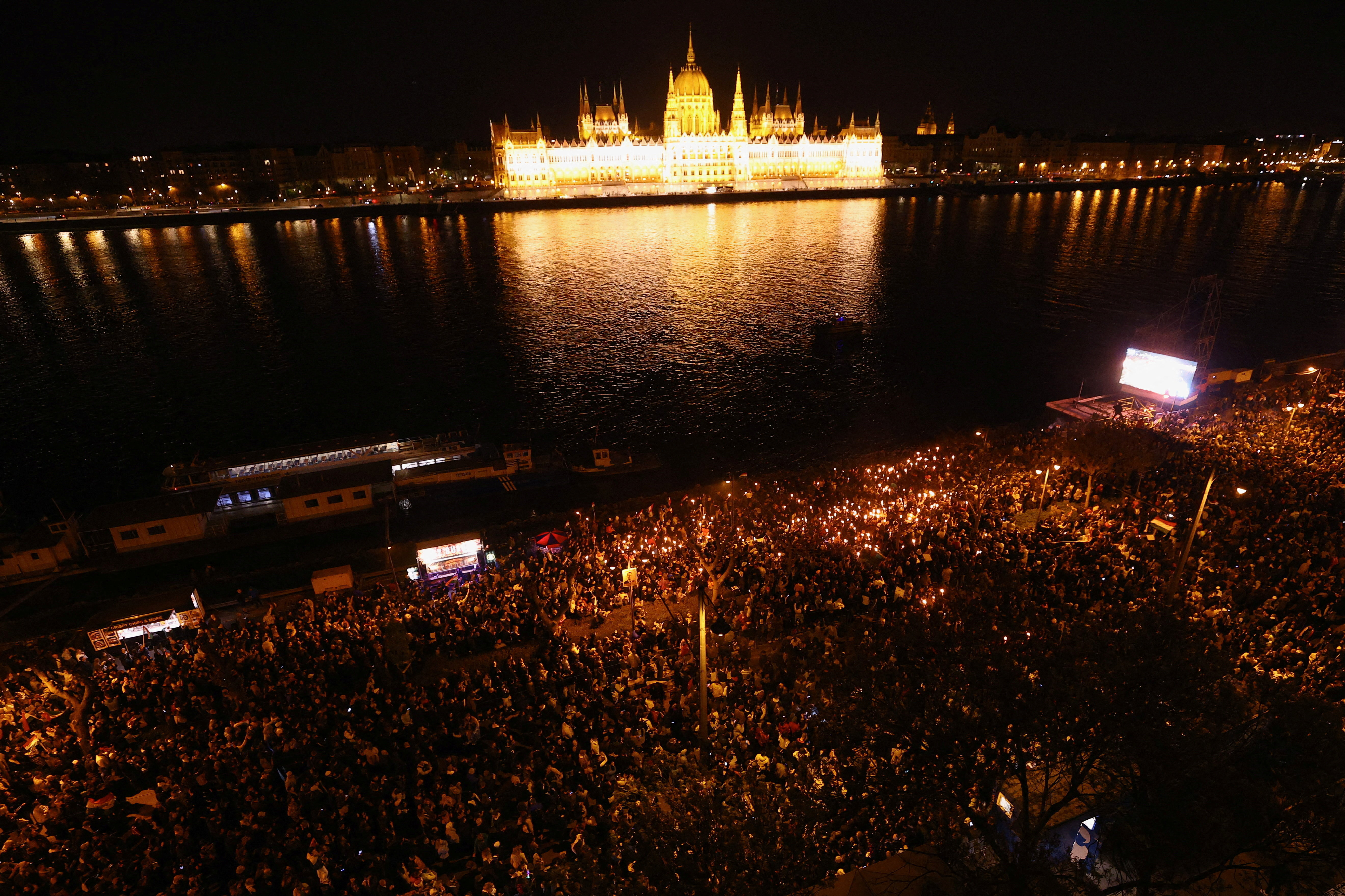 People gather to celebrate across the River Danube from the Parliament building, following the partial results of the parliamentary election, in Budapest, Hungary, April 12, 2026. REUTERS/Lisi Niesner     TPX IMAGES OF THE DAY
