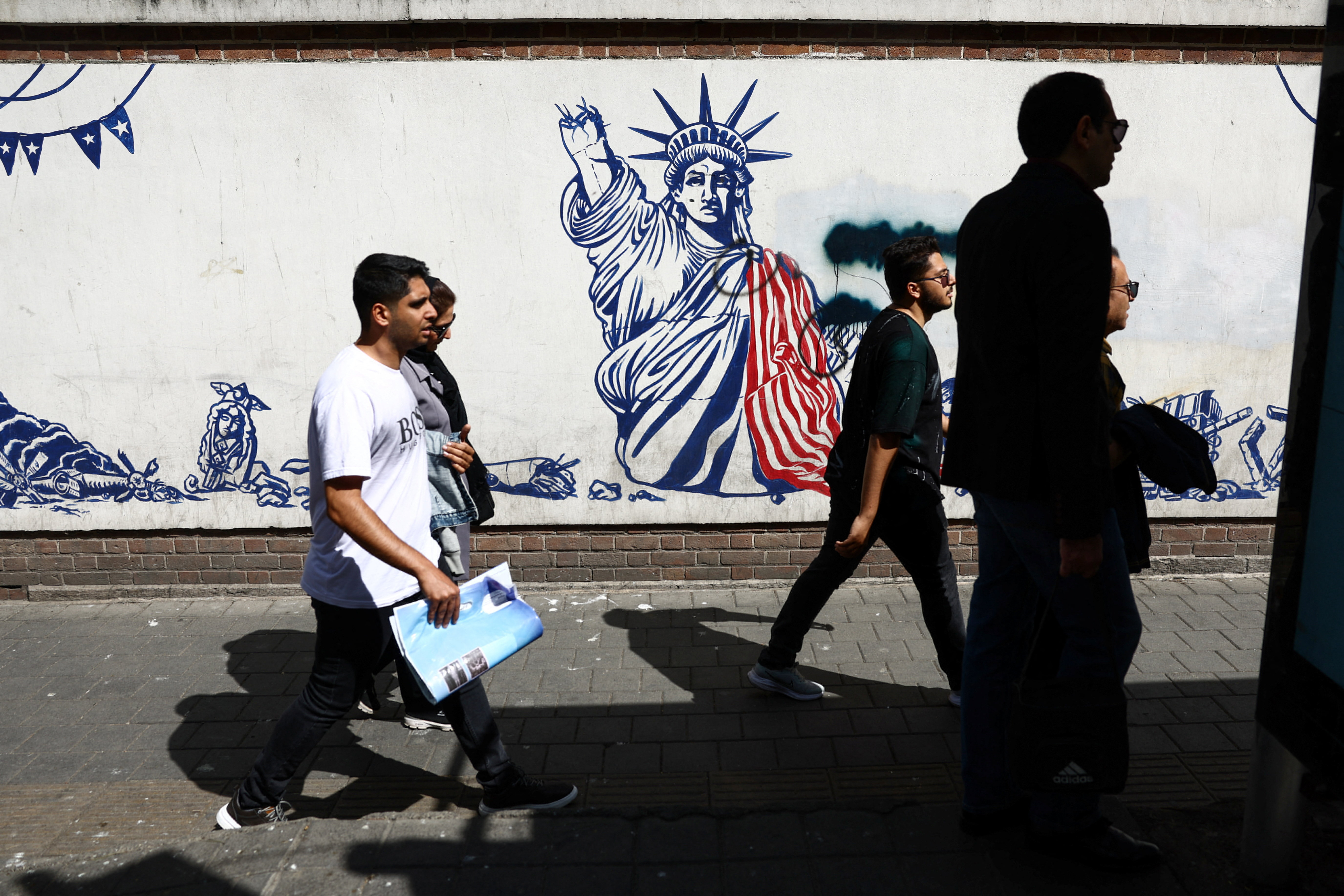 People walk past an anti-U.S. mural on a street in Tehran, Iran, April 11, 2026.
