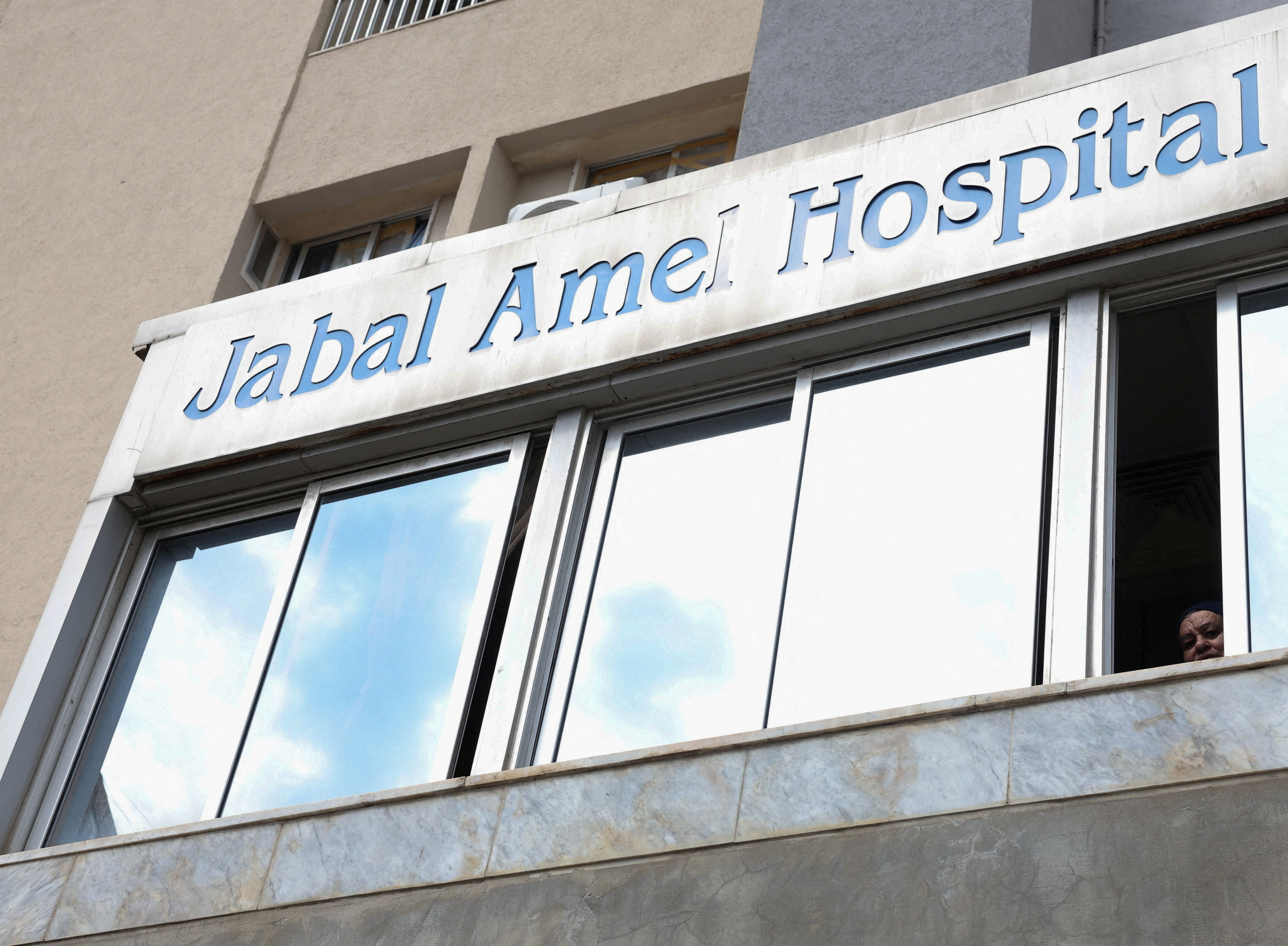 An employee at Jabal Amel University Hospital looks through a window from her rest area following an escalation between Hezbollah and Israel, in Tyre, Lebanon