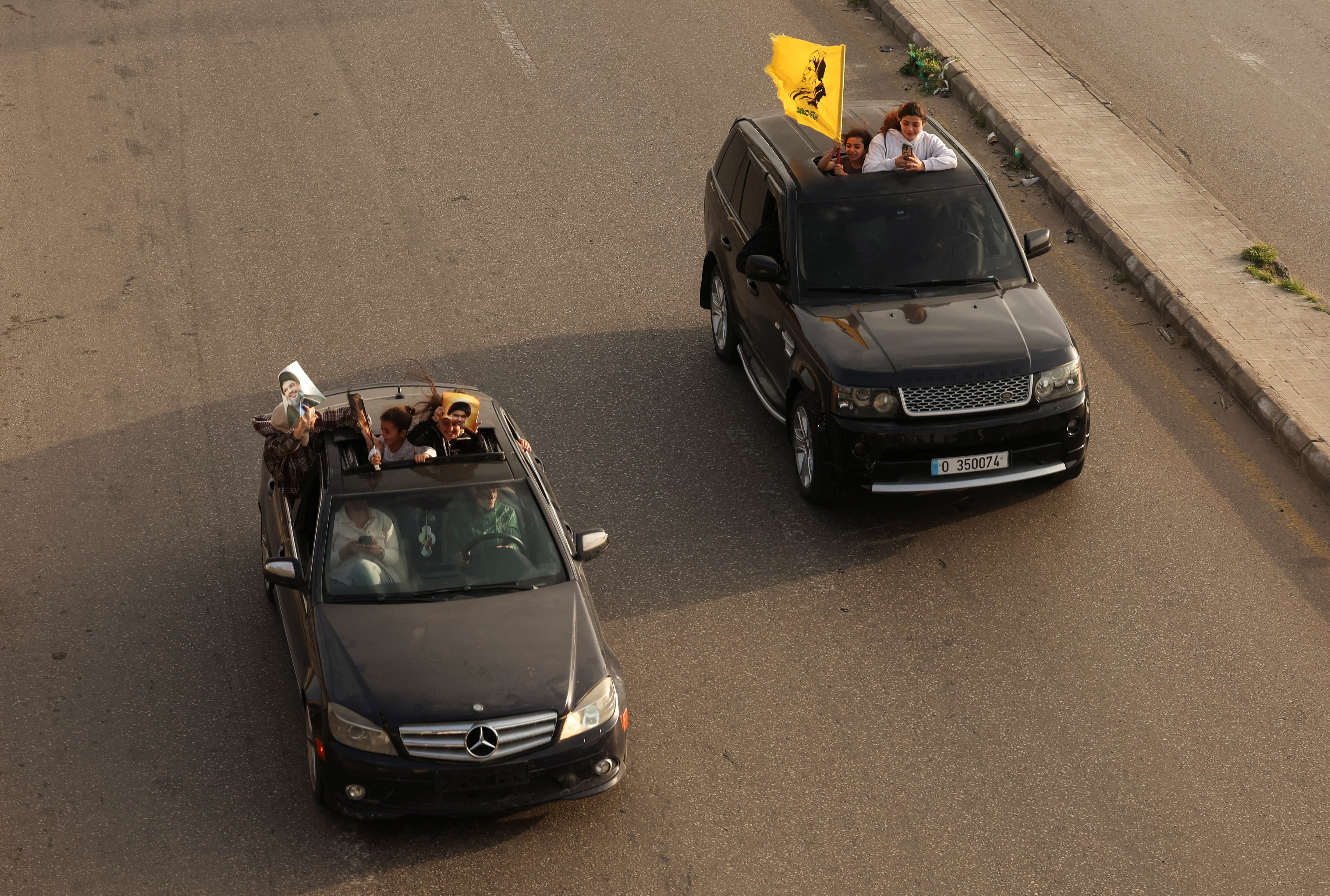 People in vehicles hold up items depicting former Hezbollah leaders Hassan Nasrallah and Hashem Safieddine, after a 10-day ceasefire between Lebanon and Israel went into effect, in Sidon, Lebanon, April 17, 2026.