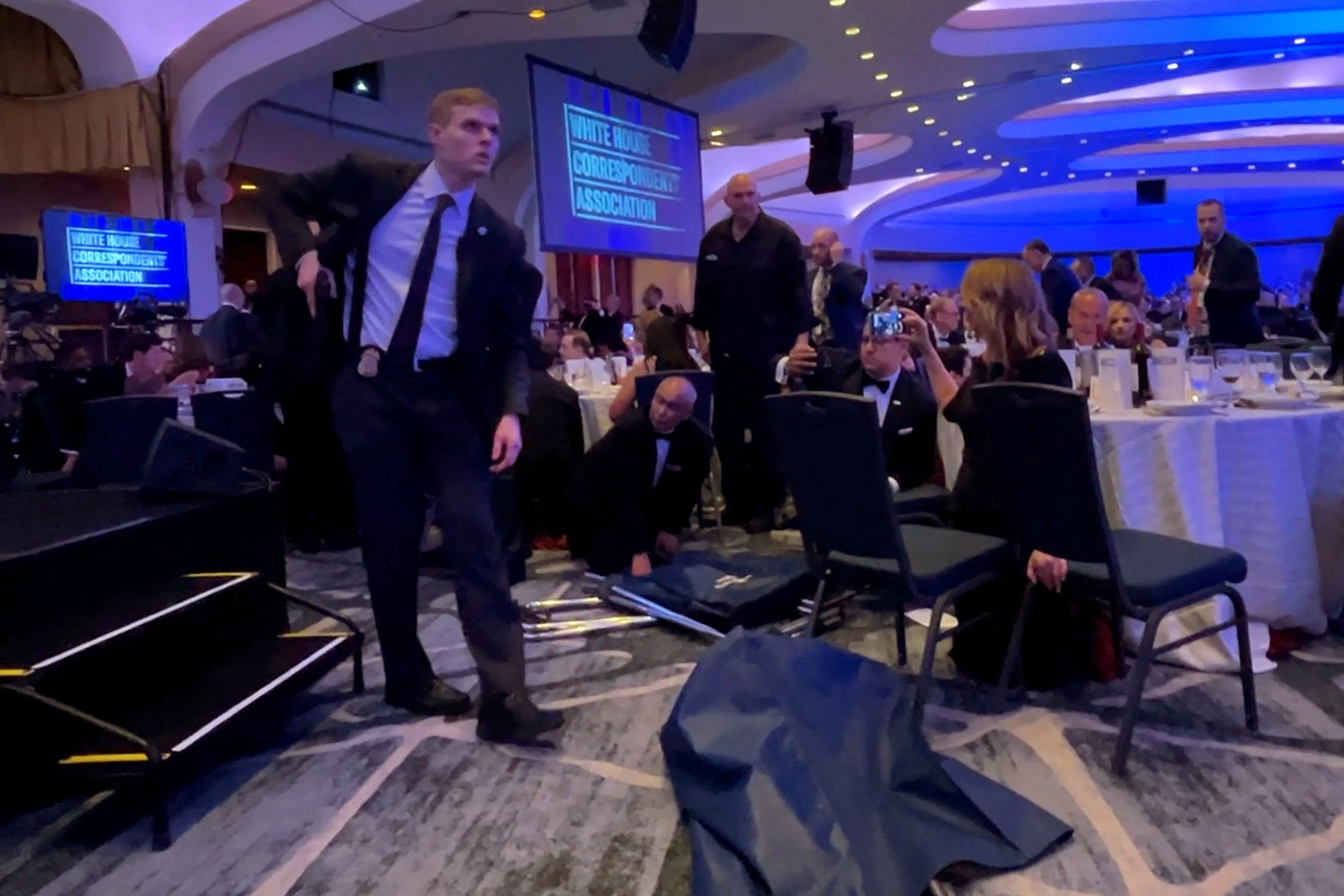 A Secret Service agent unholsters his gun, shortly after U.S. President Donald Trump was evacuated, after a man opened fire with a shotgun on security personnel outside the room during the annual White House Correspondents' Association