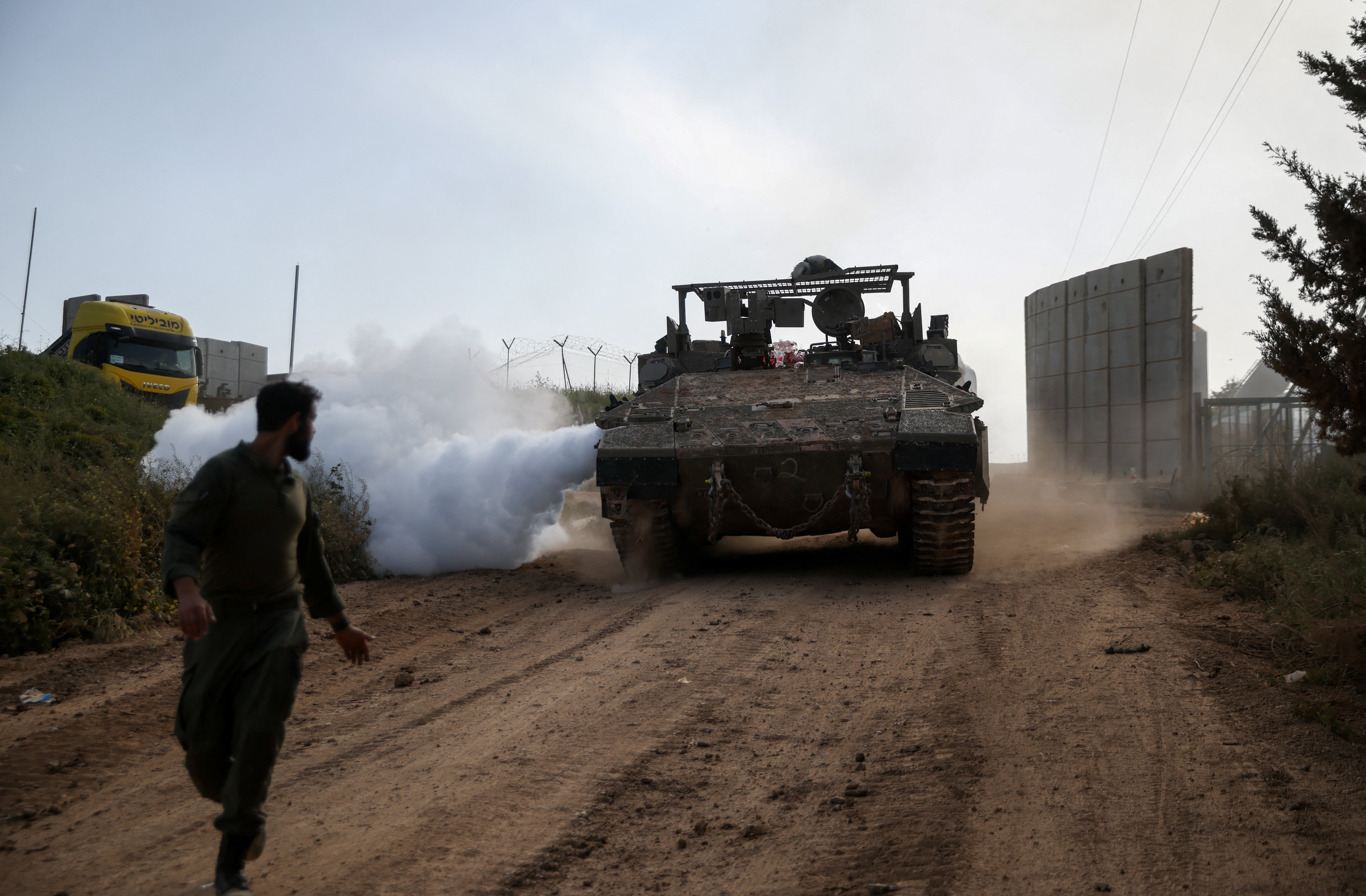 An Israeli soldier walks near a military vehicle, on the Israeli side of the Israel-Lebanon border, in northern Israel