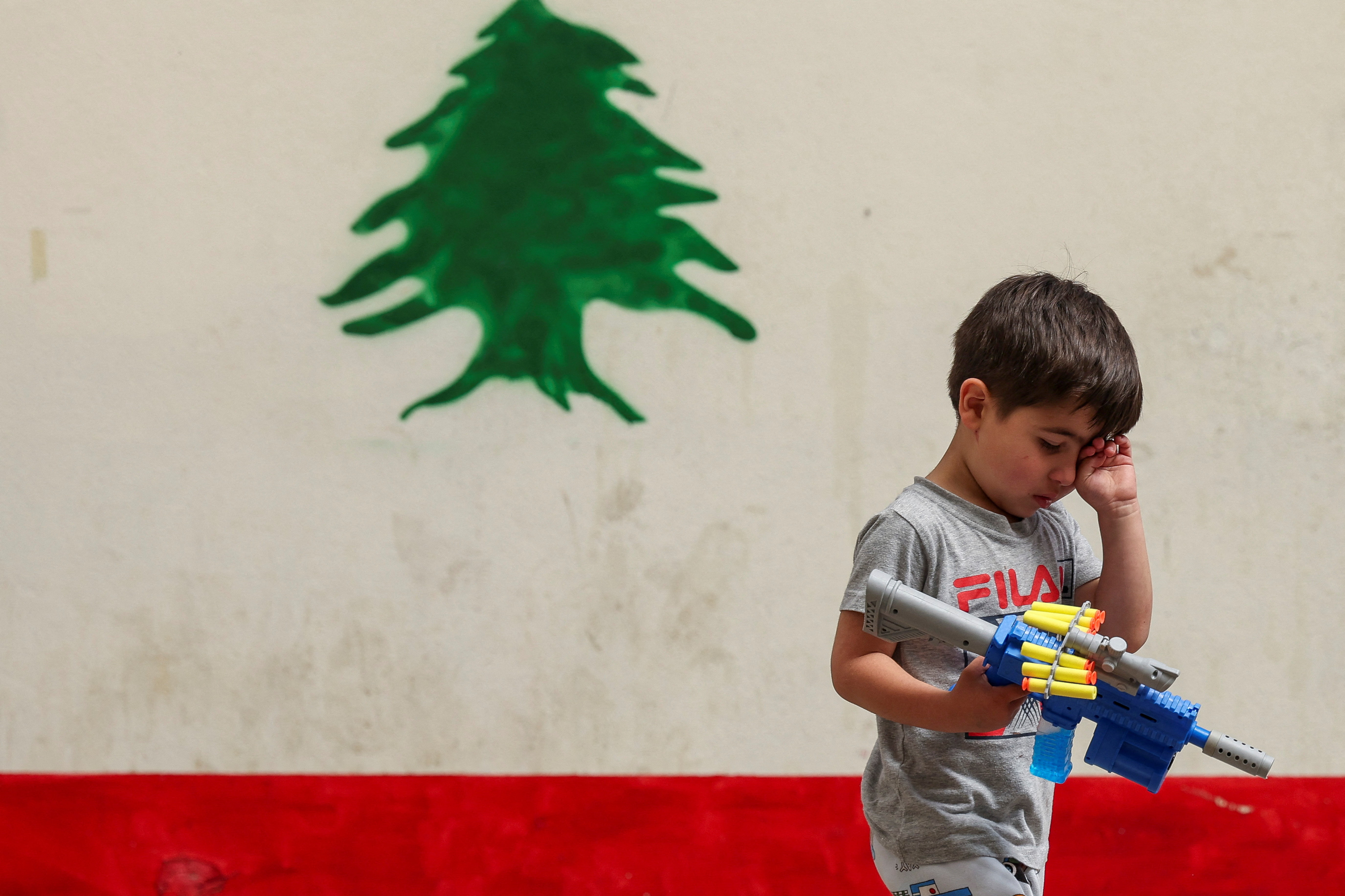 A boy, displaced from southern Lebanon amid the conflict with Israel, holds a toy gun as he walks at a school-turned shelter, near Sidon, Lebanon, May 17, 2026.