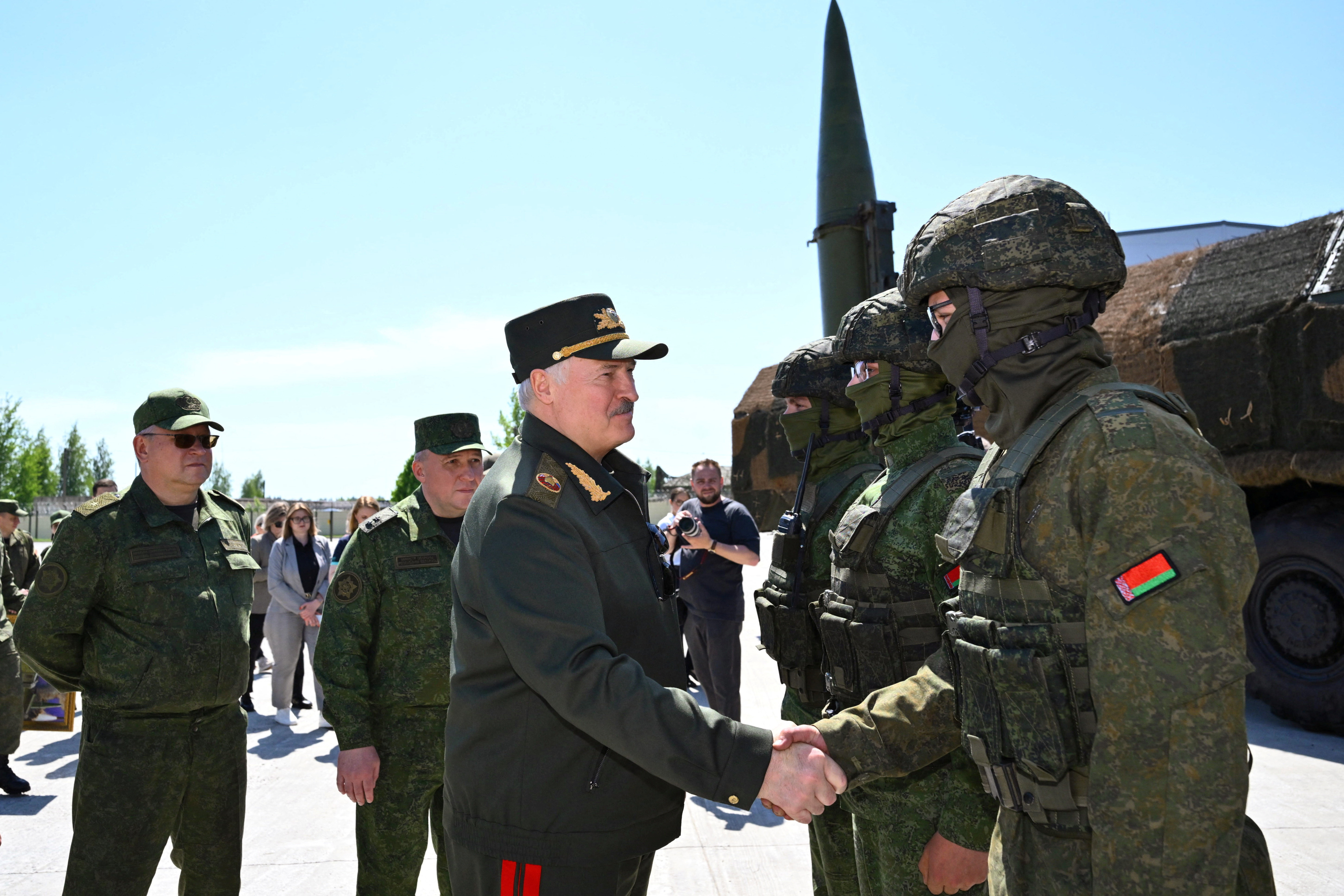 Belarusian President Alexander Lukashenko shakes hands with a service member next to the Iskander-M missile launcher as he visits a missile brigade of the Armed Forces during joint Russian-Belarusian nuclear exercises